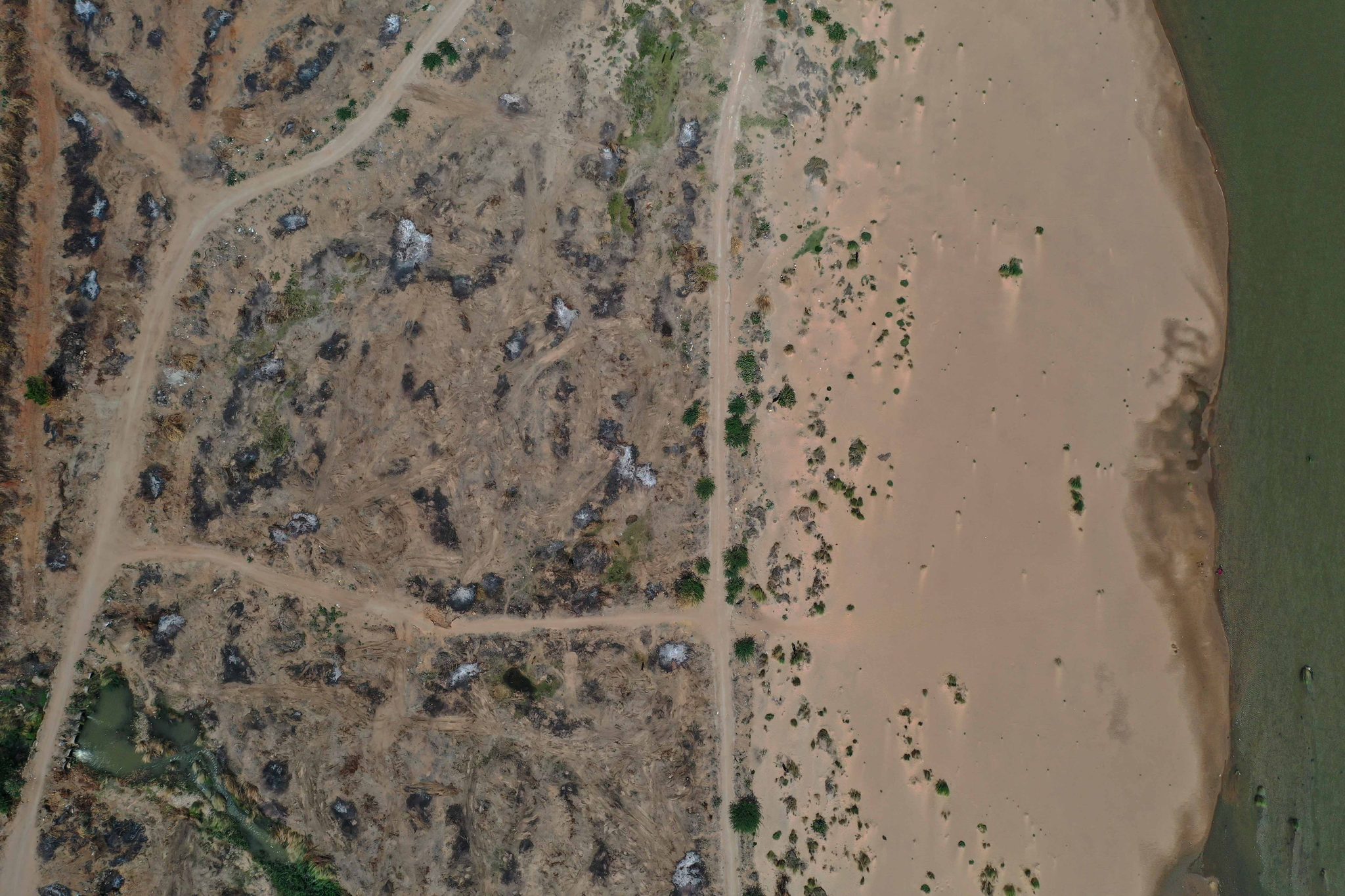 Tracks crisscross a sandy stretch of the riverbed, seen from above.