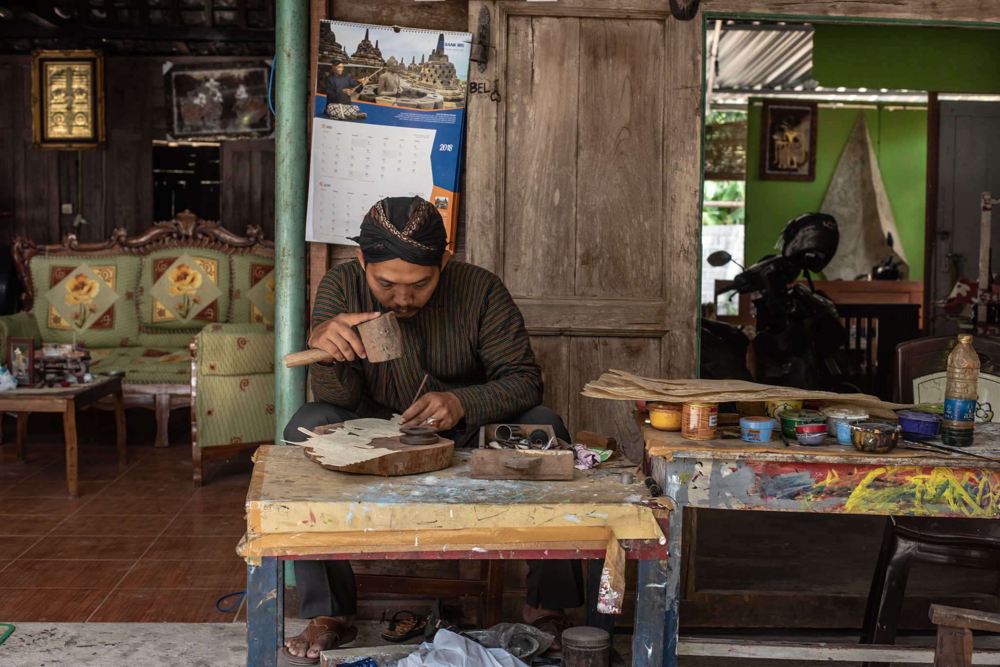 Dhidot, a shadow puppet maker, meticulously hammers designs into a new puppet