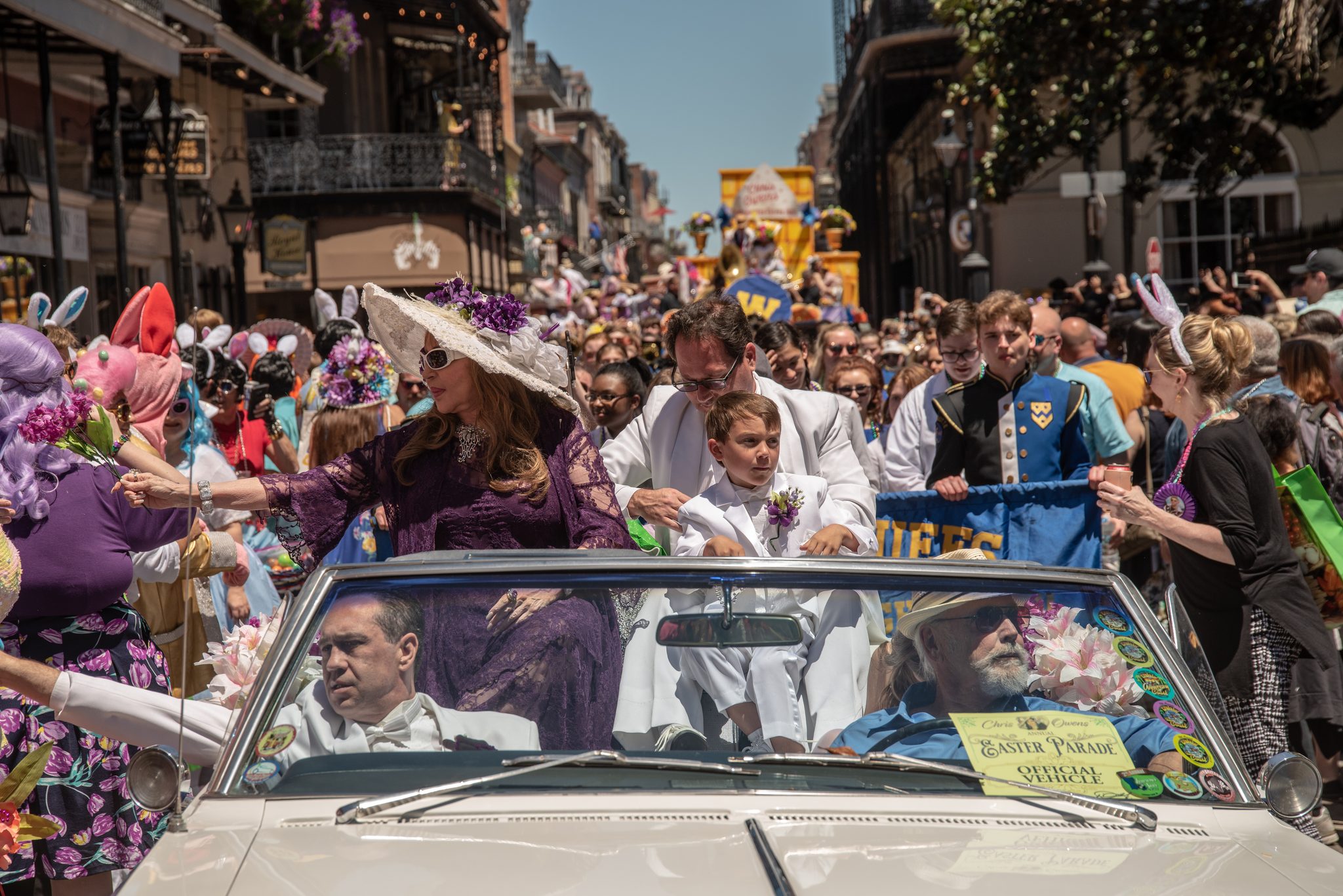 The Easter parade inches through the French Quarter, hats and lace and outstretched hands reaching from every side of the car.