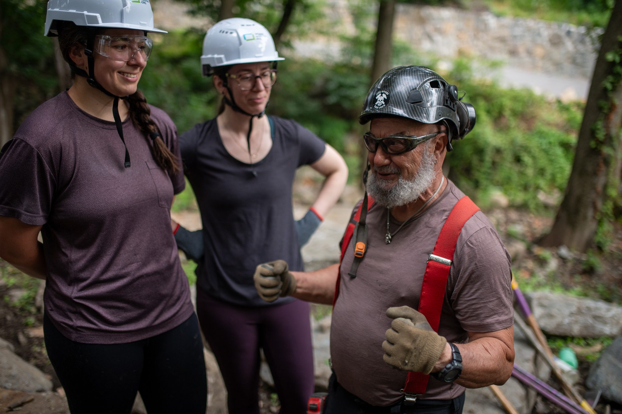Two crew members share a laugh with the man in red suspenders.