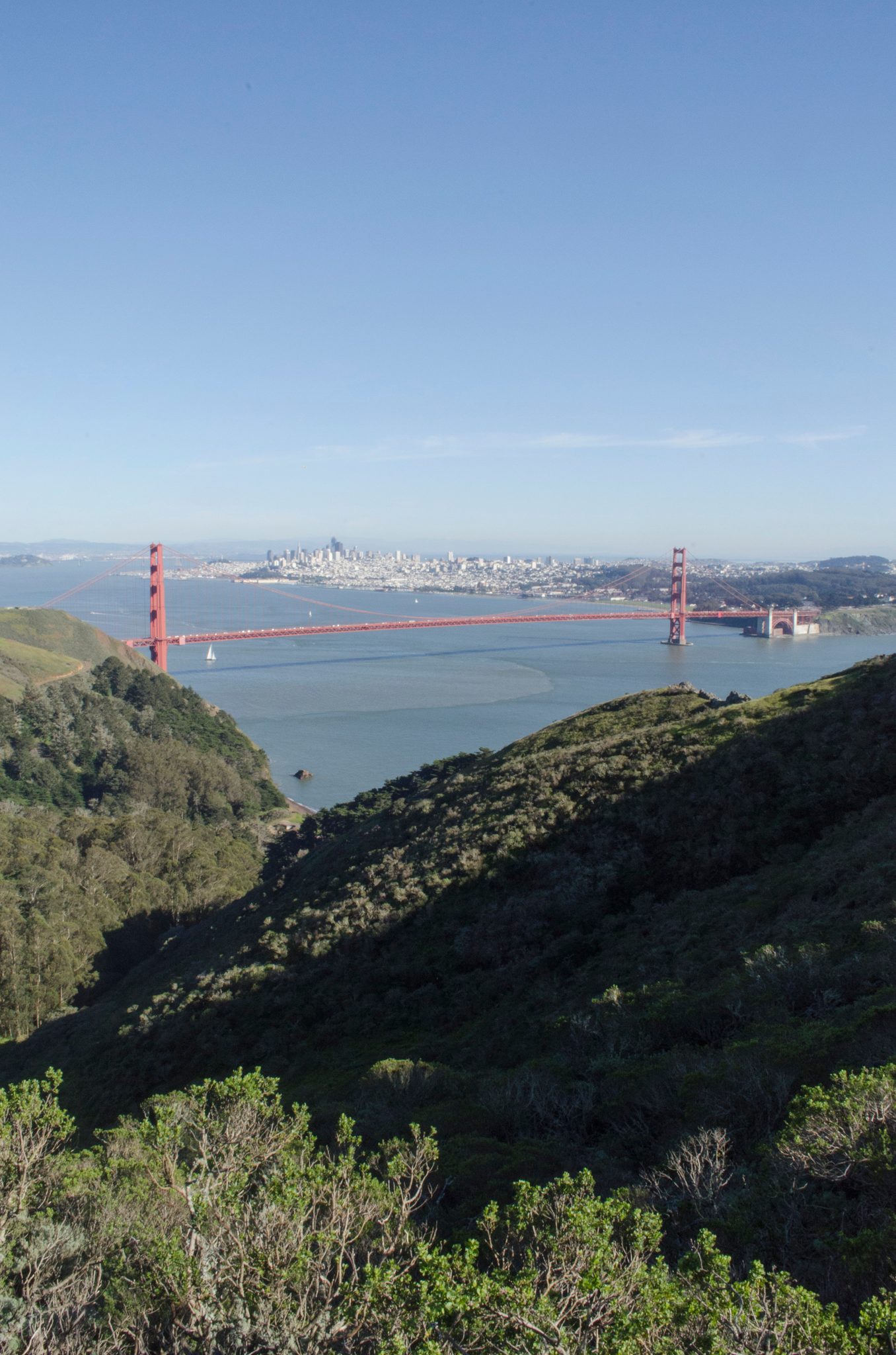 The Golden Gate Bridge crosses the bay, the city beyond.