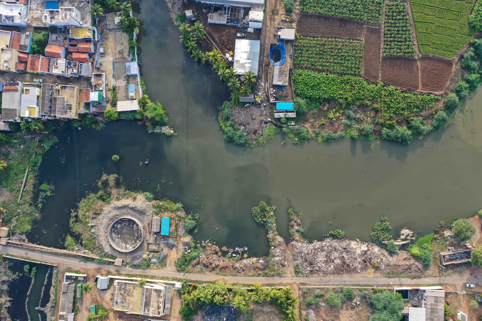 A town presses against the river, a circular pit on the far bank.
