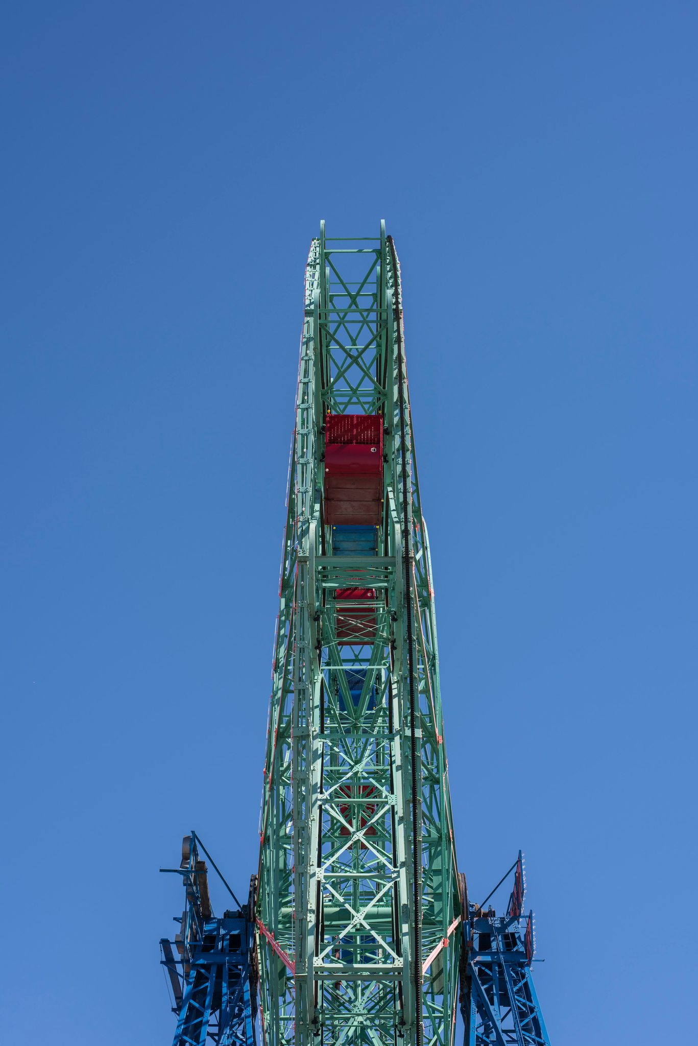 The top of a Ferris wheel reaches into the clear blue sky.