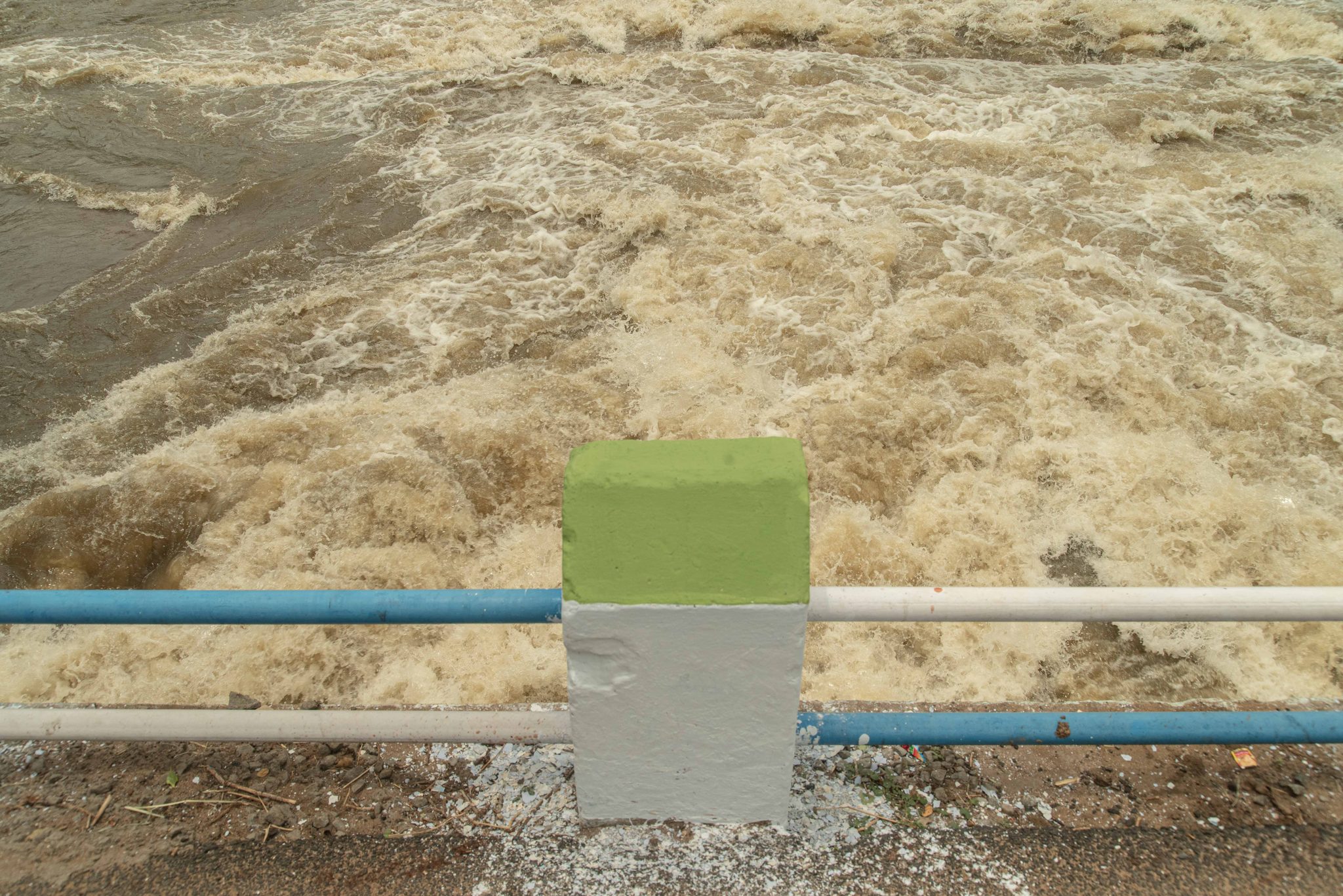 Brown floodwater surges past the railing.