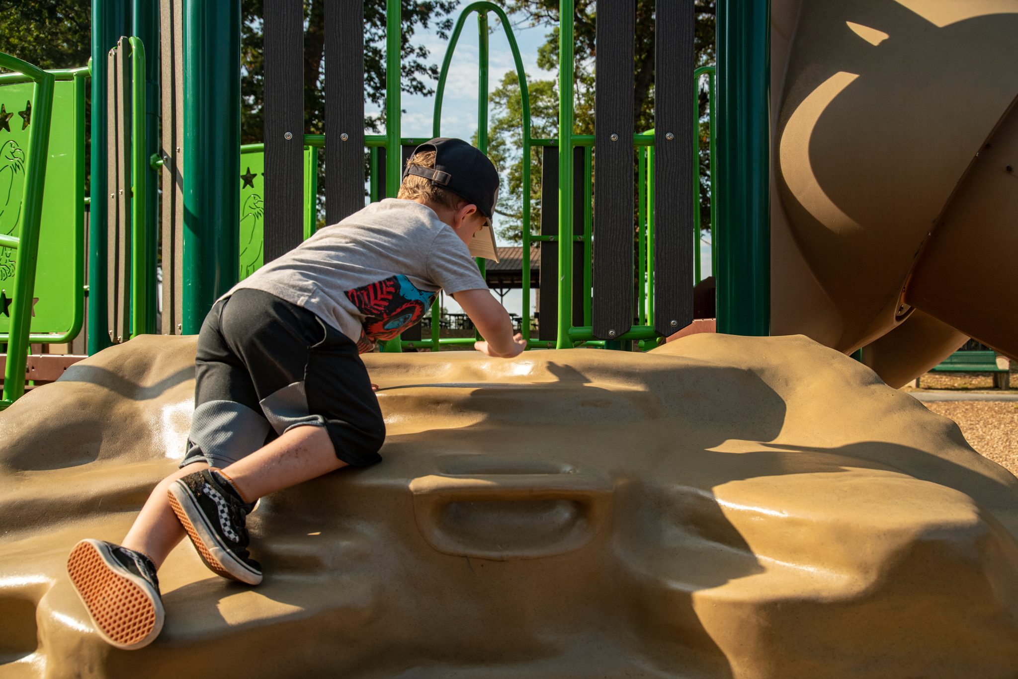 A boy scrambles up the rock wall on hands and knees.