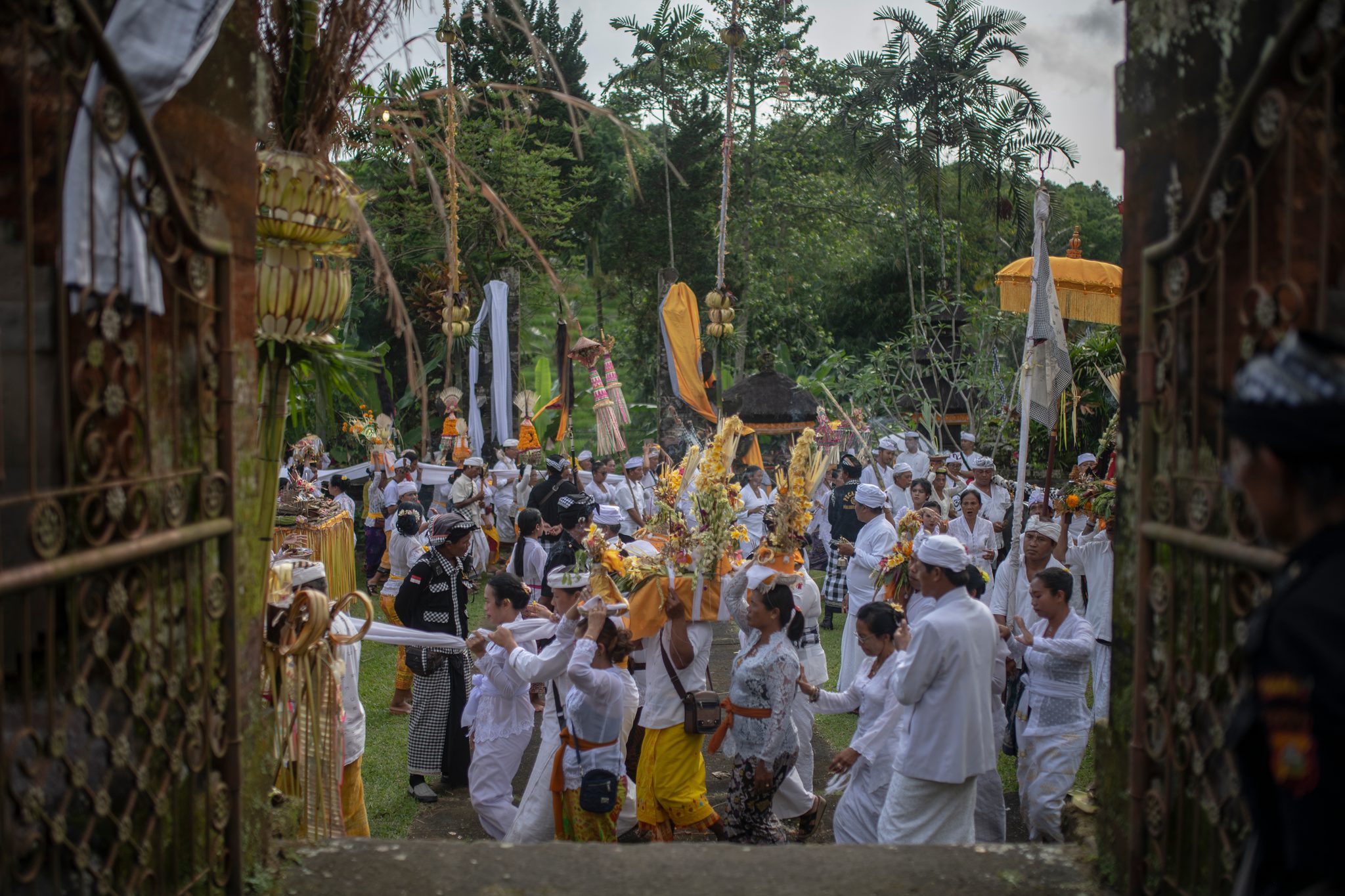 The procession pours through the gate carrying towers of offerings.