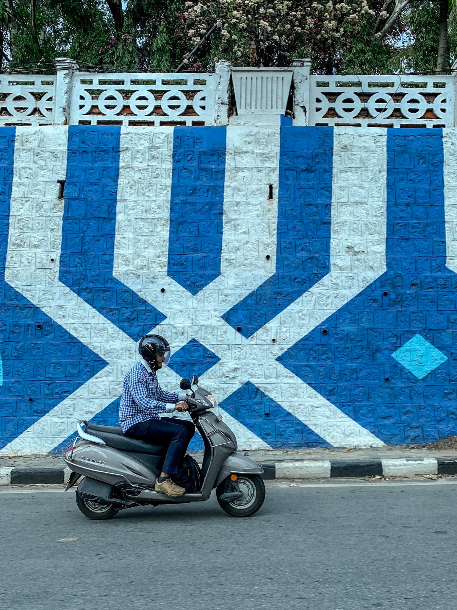 A scooter passes a wall painted in bold blue and white.