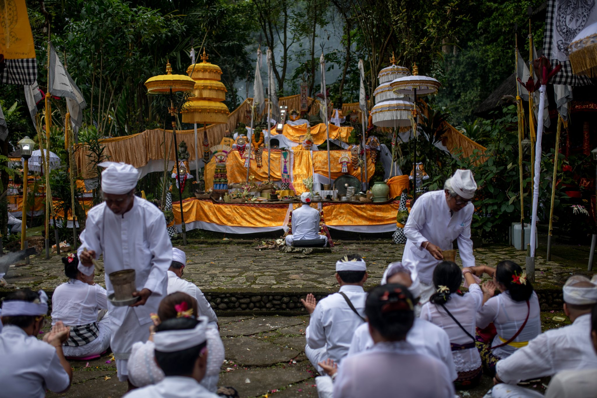 Temple elders move through the rows sprinkling holy water over bowed heads.