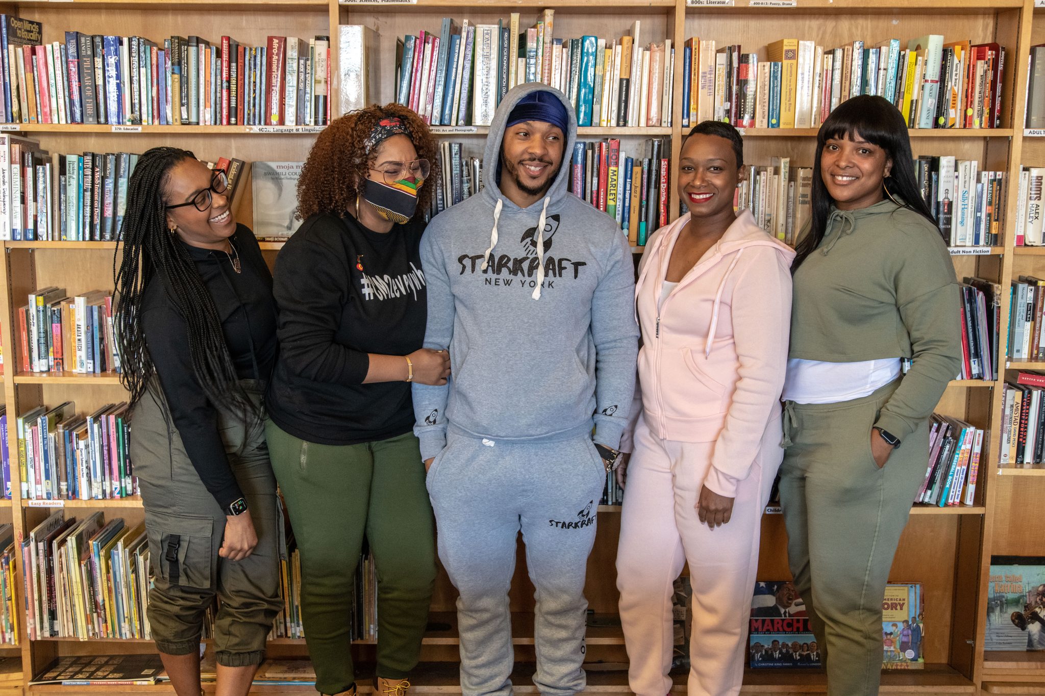 The whole group lines up in front of the library shelves.