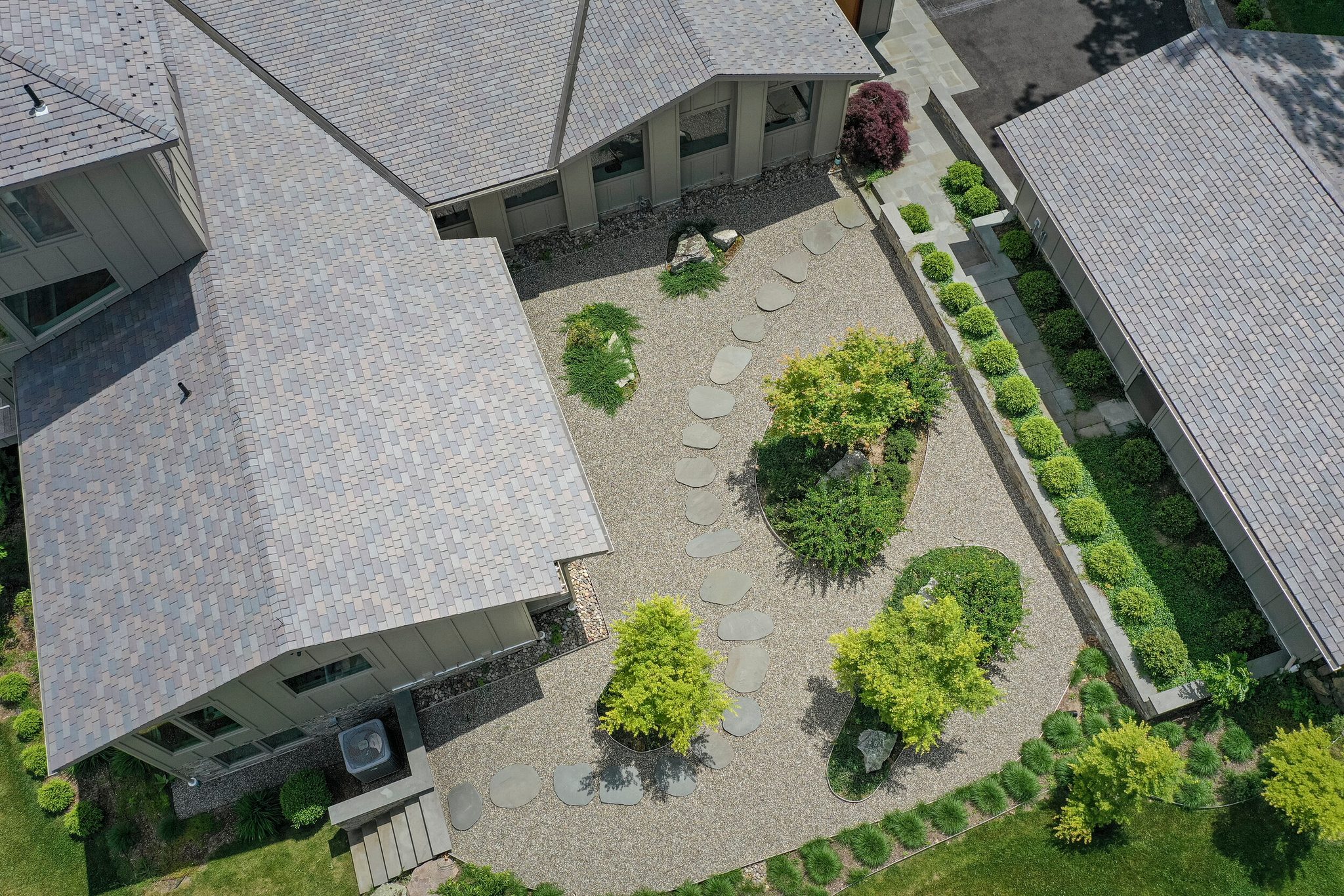 Straight down from the drone in early June, a courtyard of stepping stones and shrubs between gray roofs.