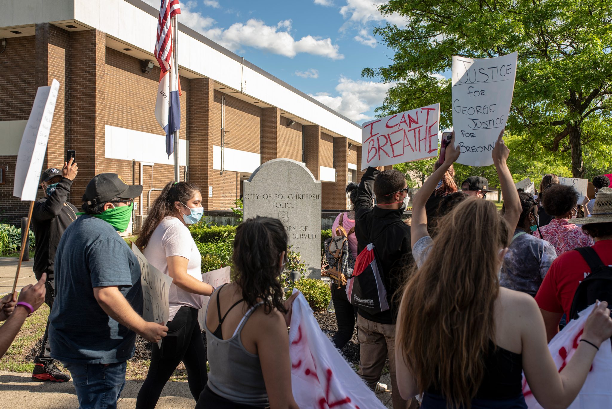 Marchers pass the city police building carrying signs that read I Can't Breathe and Justice for George, Justice for Breonna.