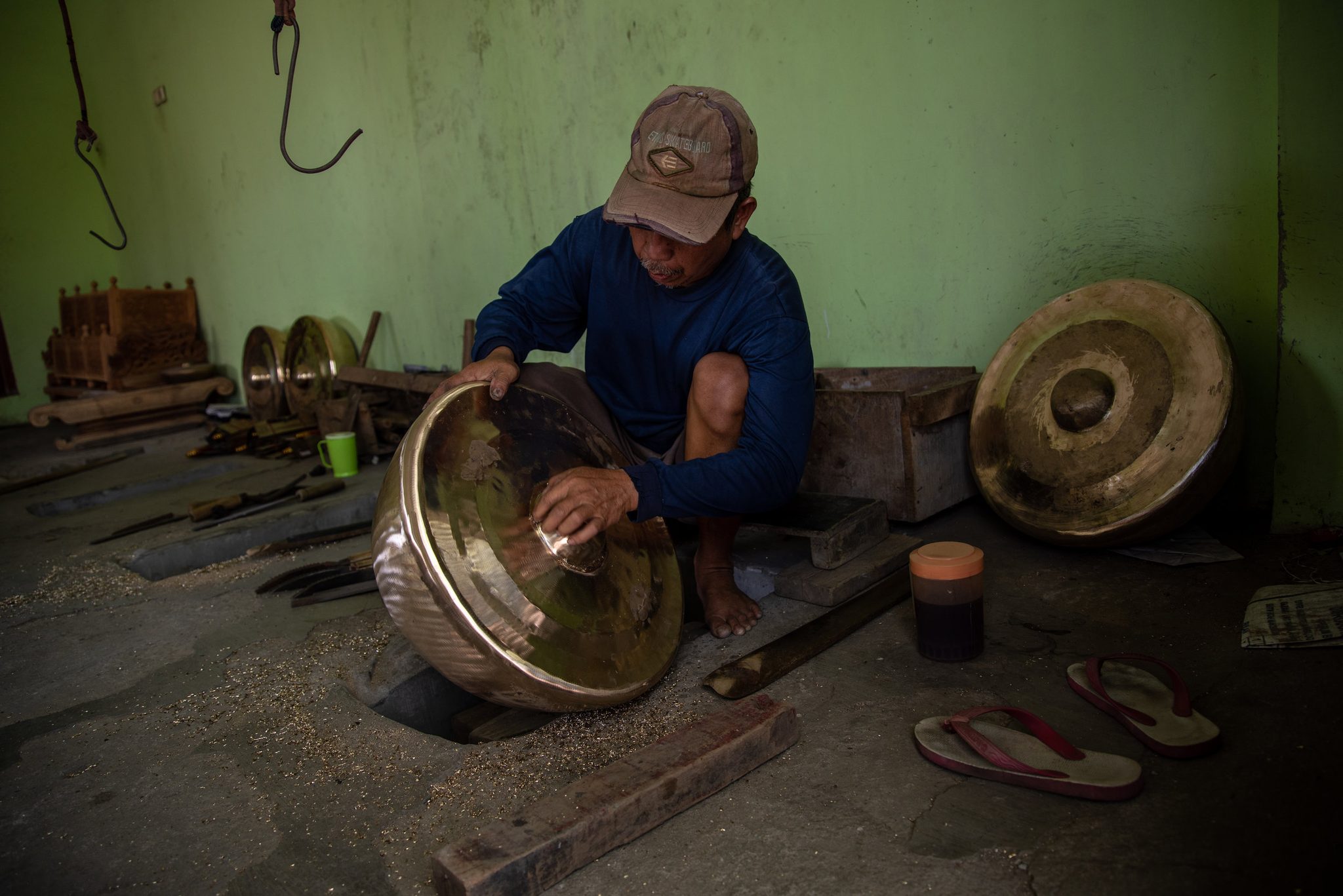A craftsman polishes the inside of a gong by hand, its surface turning to gold.