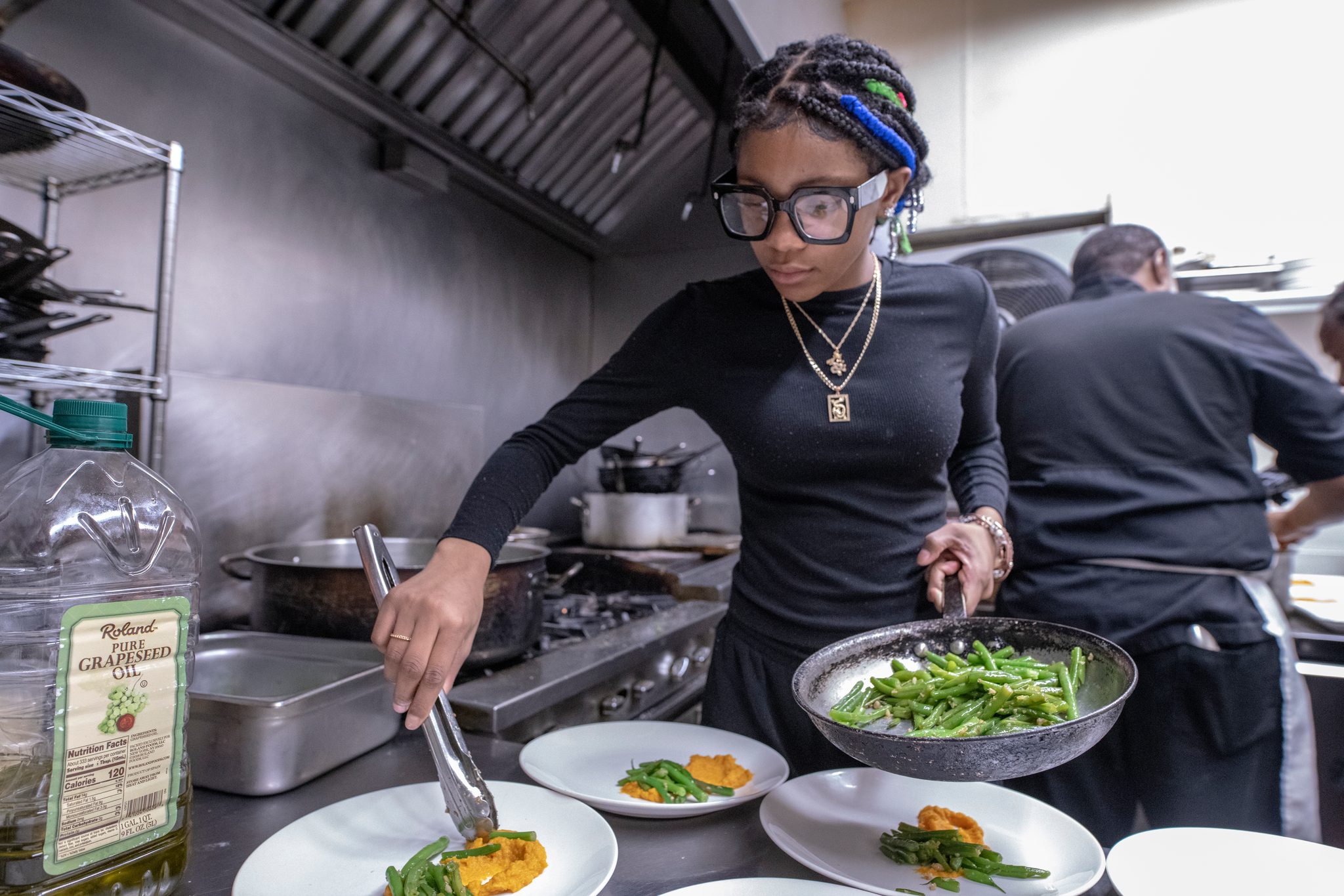 Tongs, greens and focus: plating in the restaurant kitchen.