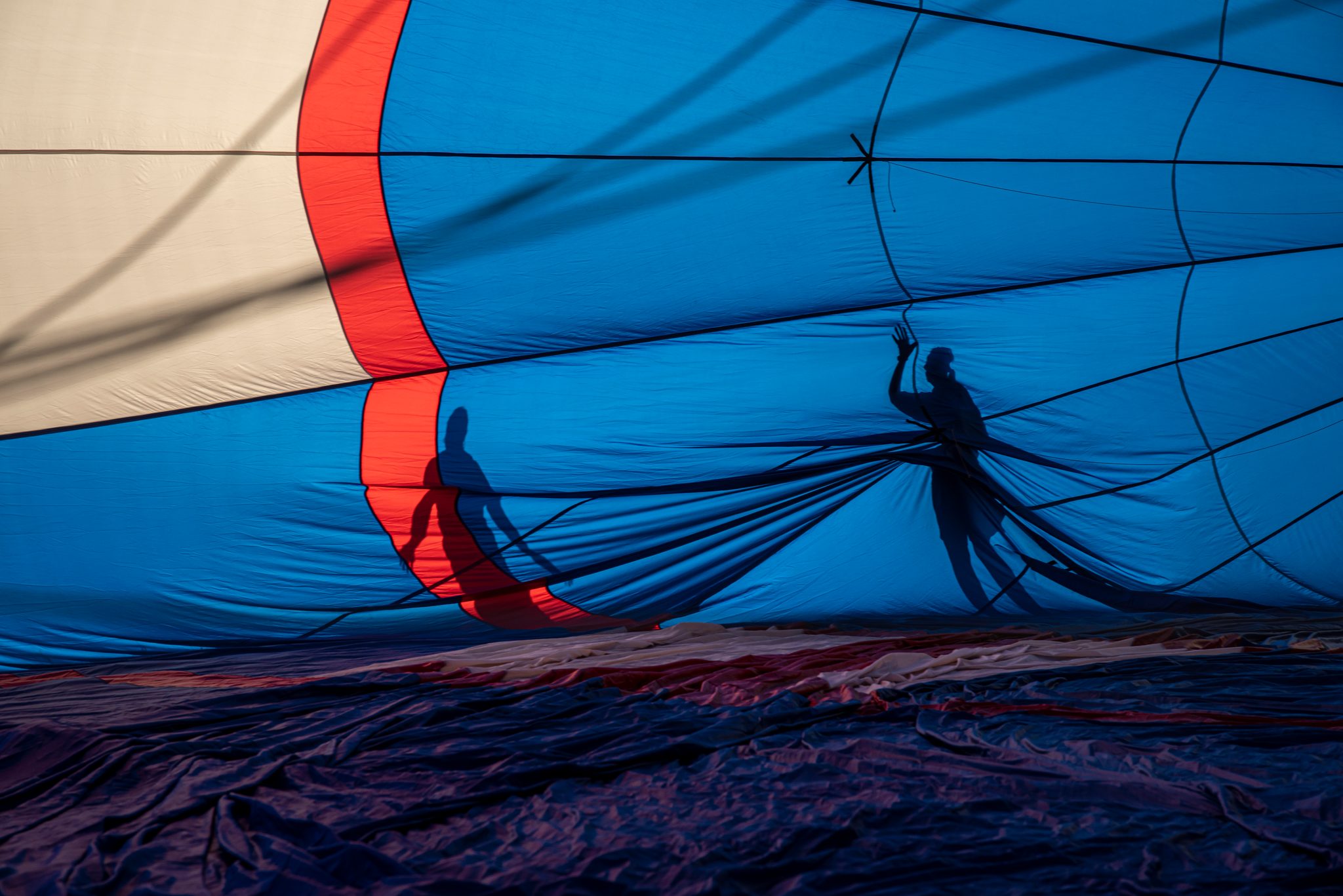 Shadows of the crew stretch across the fabric as the balloon takes its first breath.