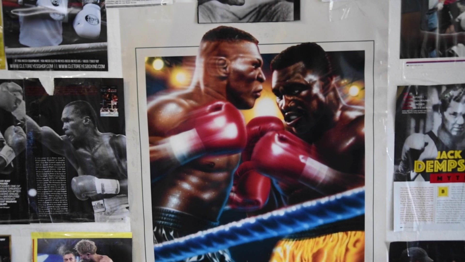 Inside, the walls are papered with fight posters and magazine pages, a painted pair of heavyweights trading right hands at the center.