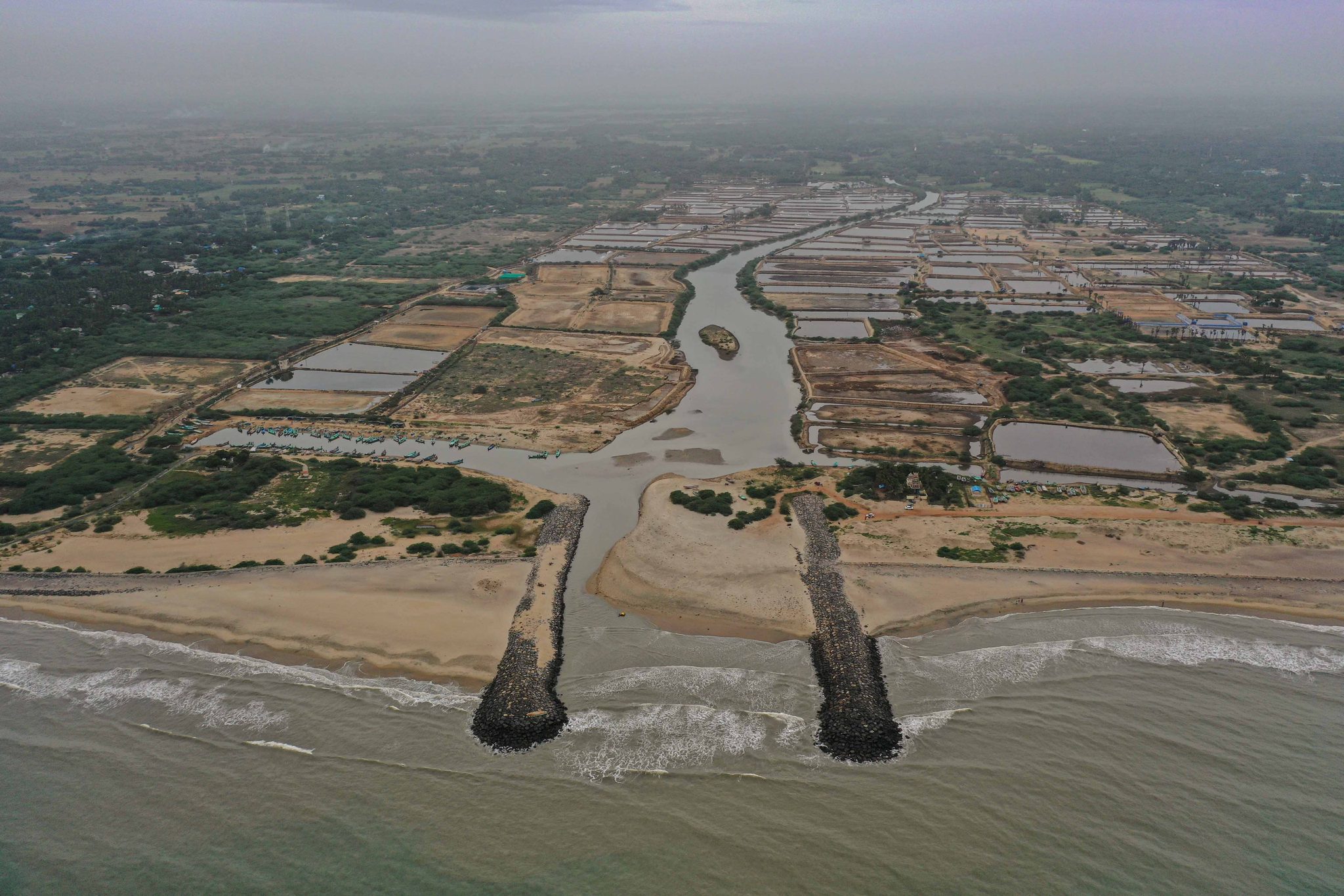 The river cuts through a coast of ponds and paddies to reach the sea.