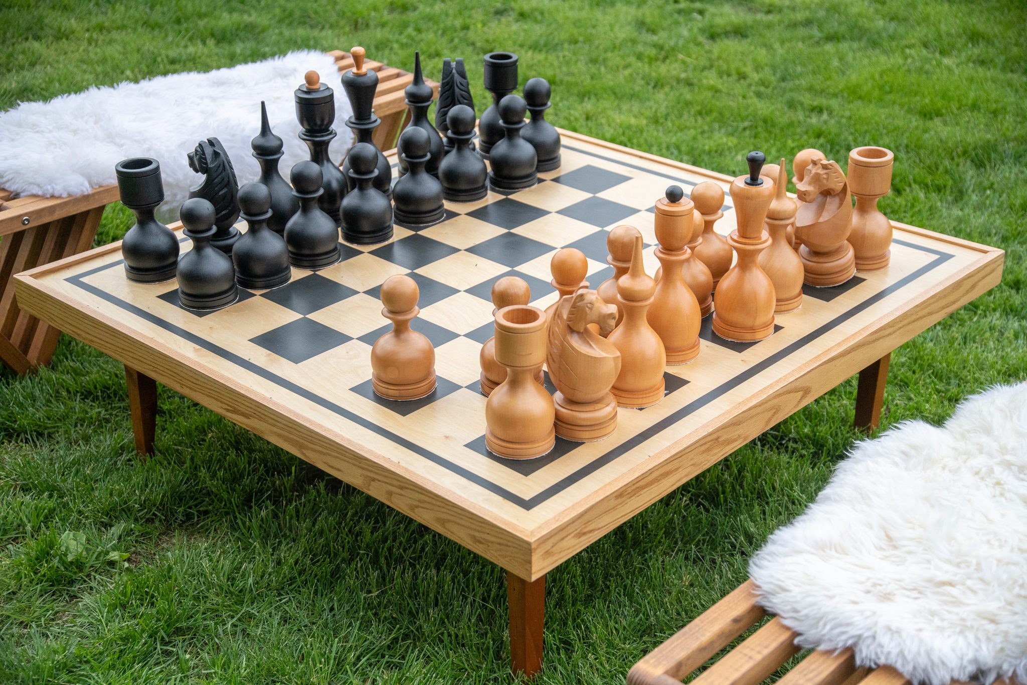 A giant chess set waits on the lawn between two sheepskin benches.
