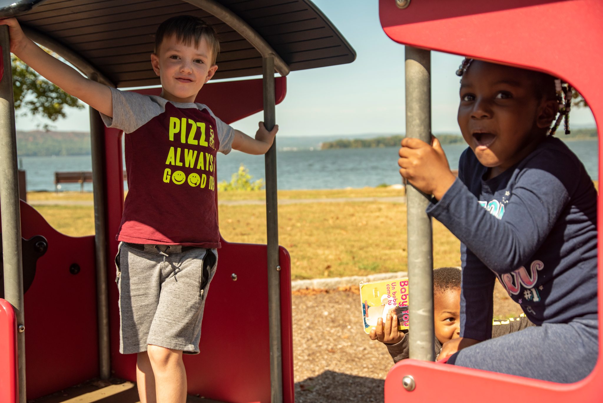 The playground train fills up fast, the river glittering just beyond the grass.