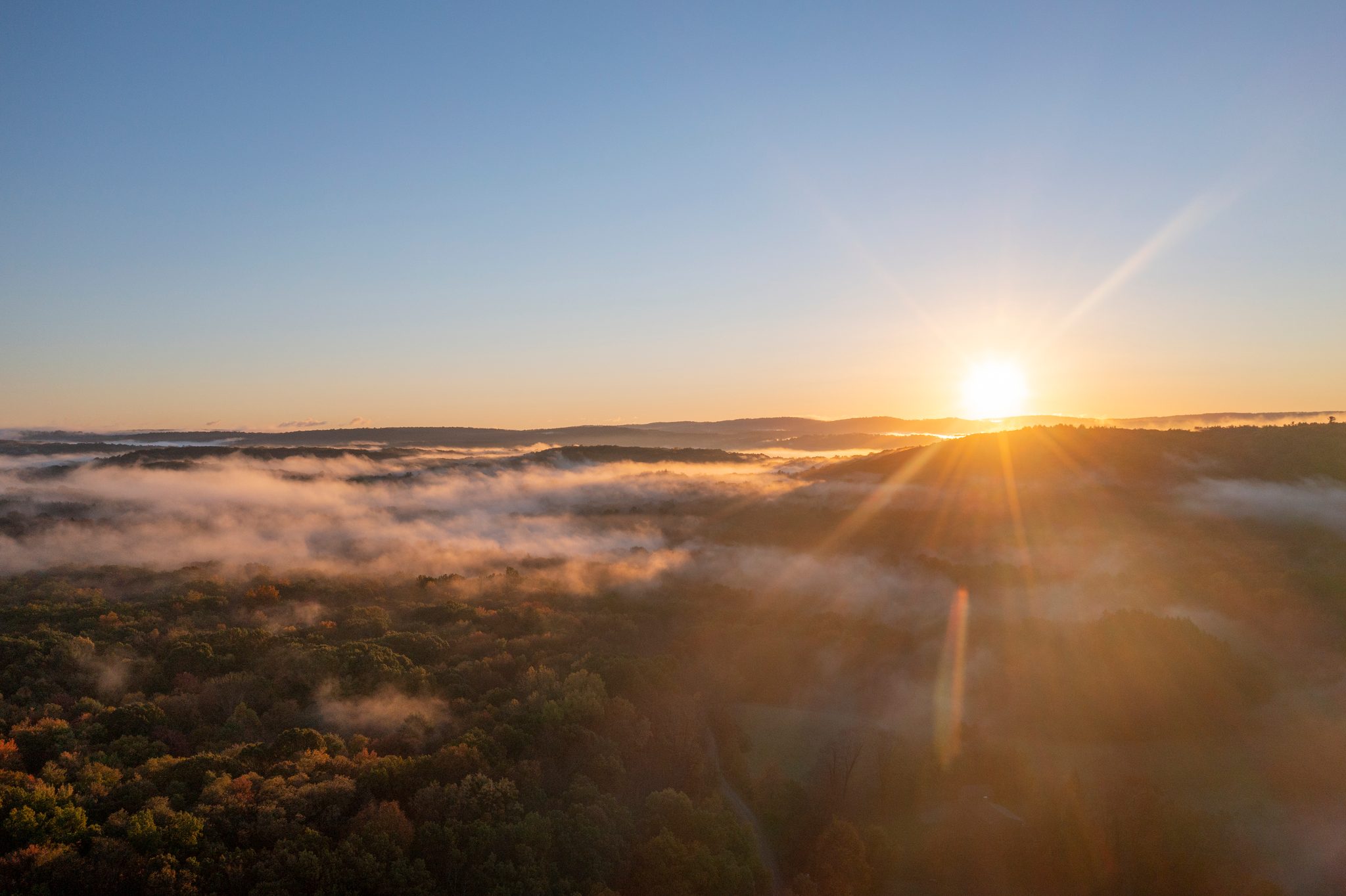The sun clears the ridge and sets the fog alight.