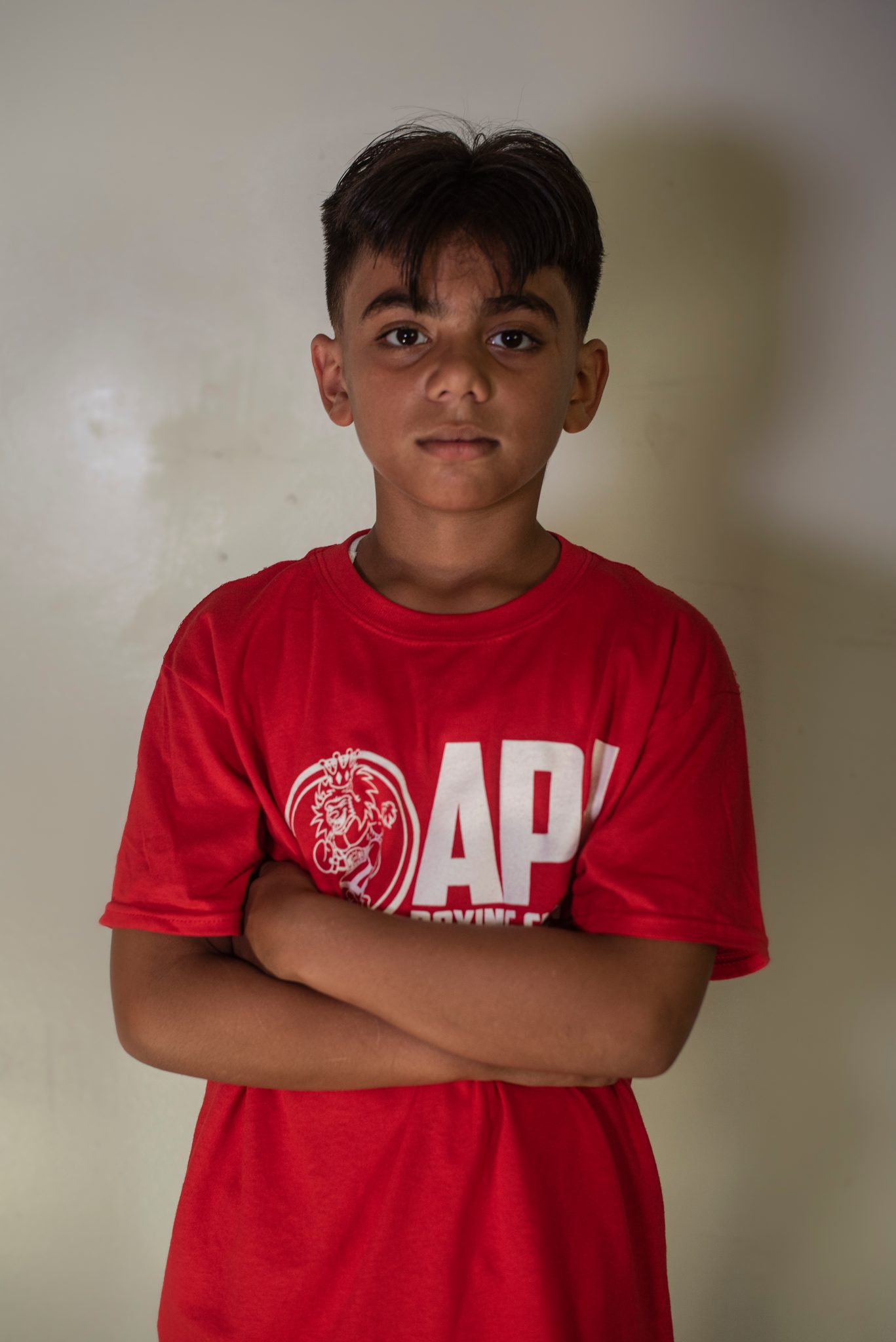 Arms crossed and chin level, a young boxer with a fresh fade sizes up the lens.
