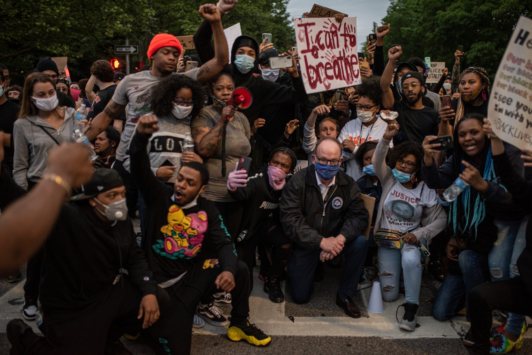 The crowd takes a knee with fists raised, an I Can't Breathe sign held high above them.