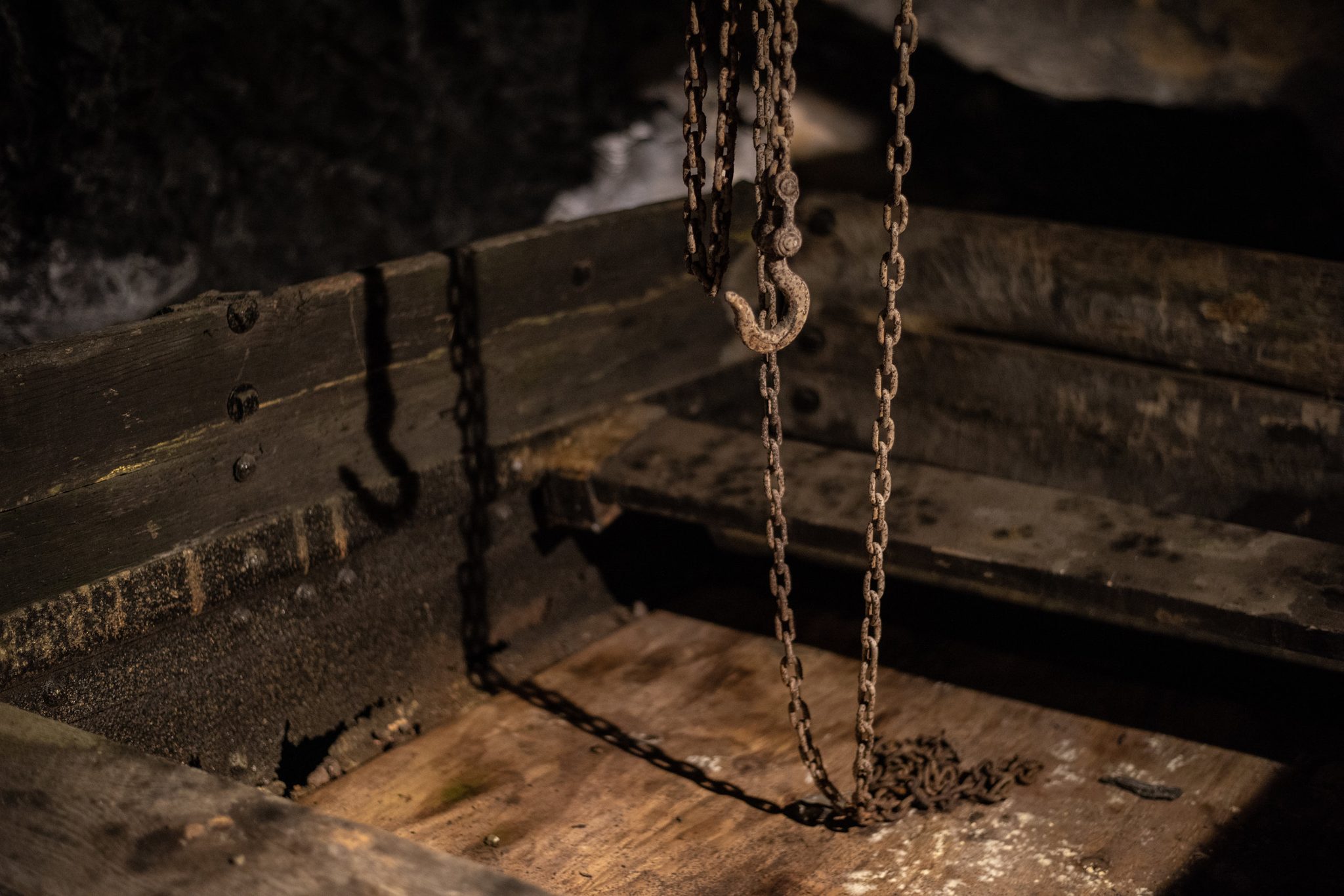 Chains hang over a wooden coal car deep underground.