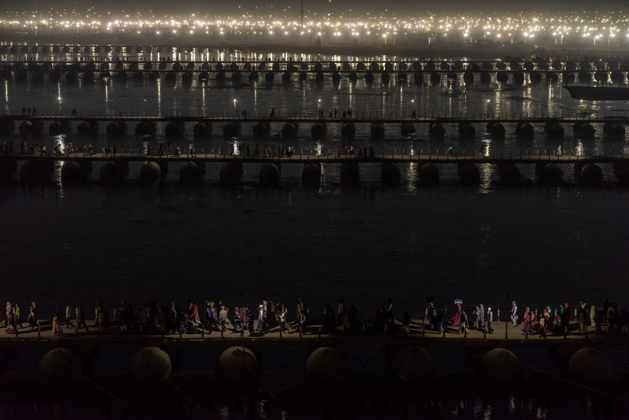 At night the pontoon bridges glow in rows, pilgrims crossing in silhouette.