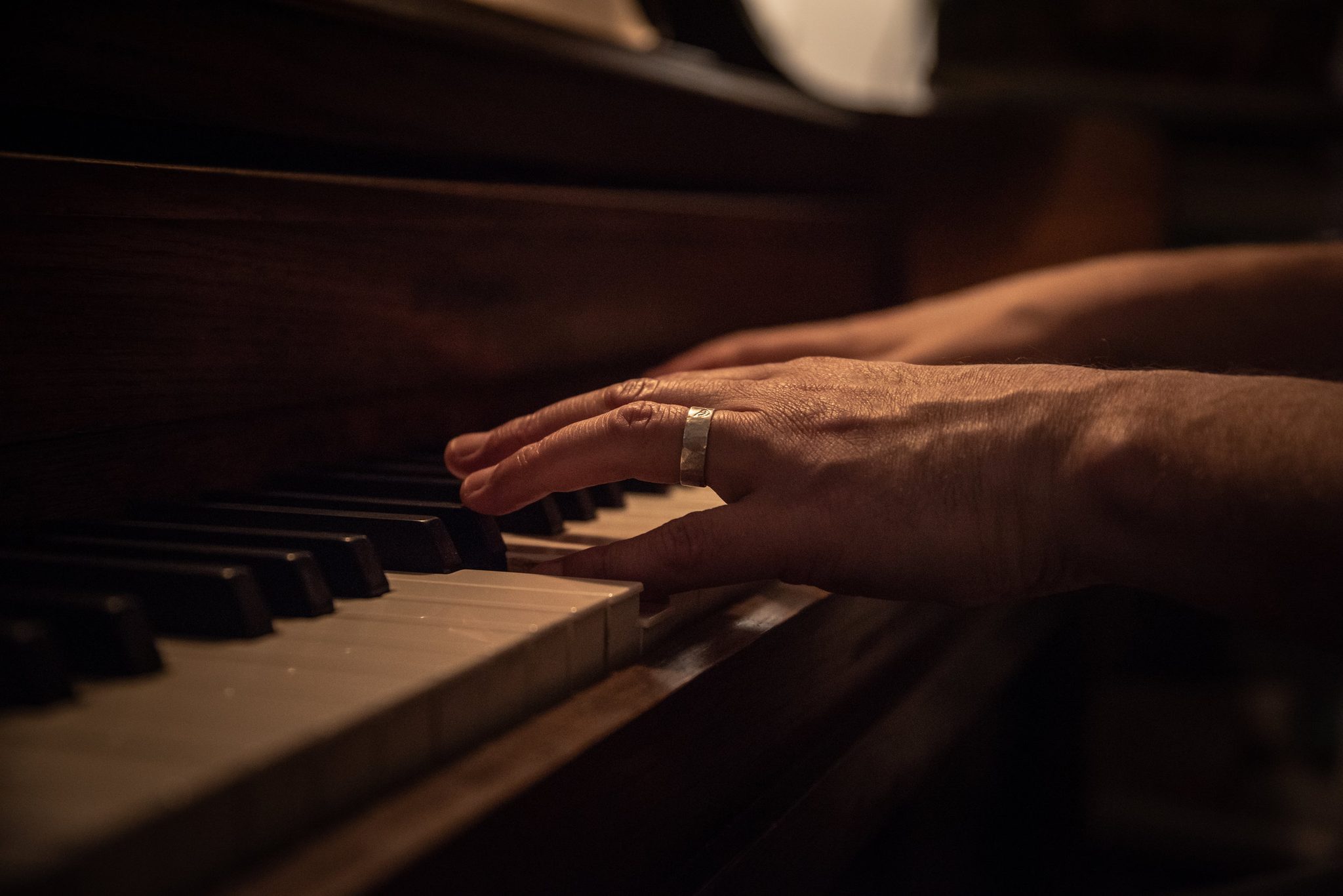 A ringed hand rests on the keys at home, where the composing happens.