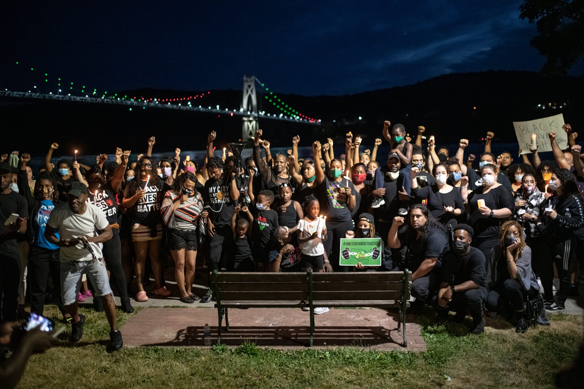 Fists raised, the whole crowd gathers for one picture beneath the lit Mid-Hudson Bridge.
