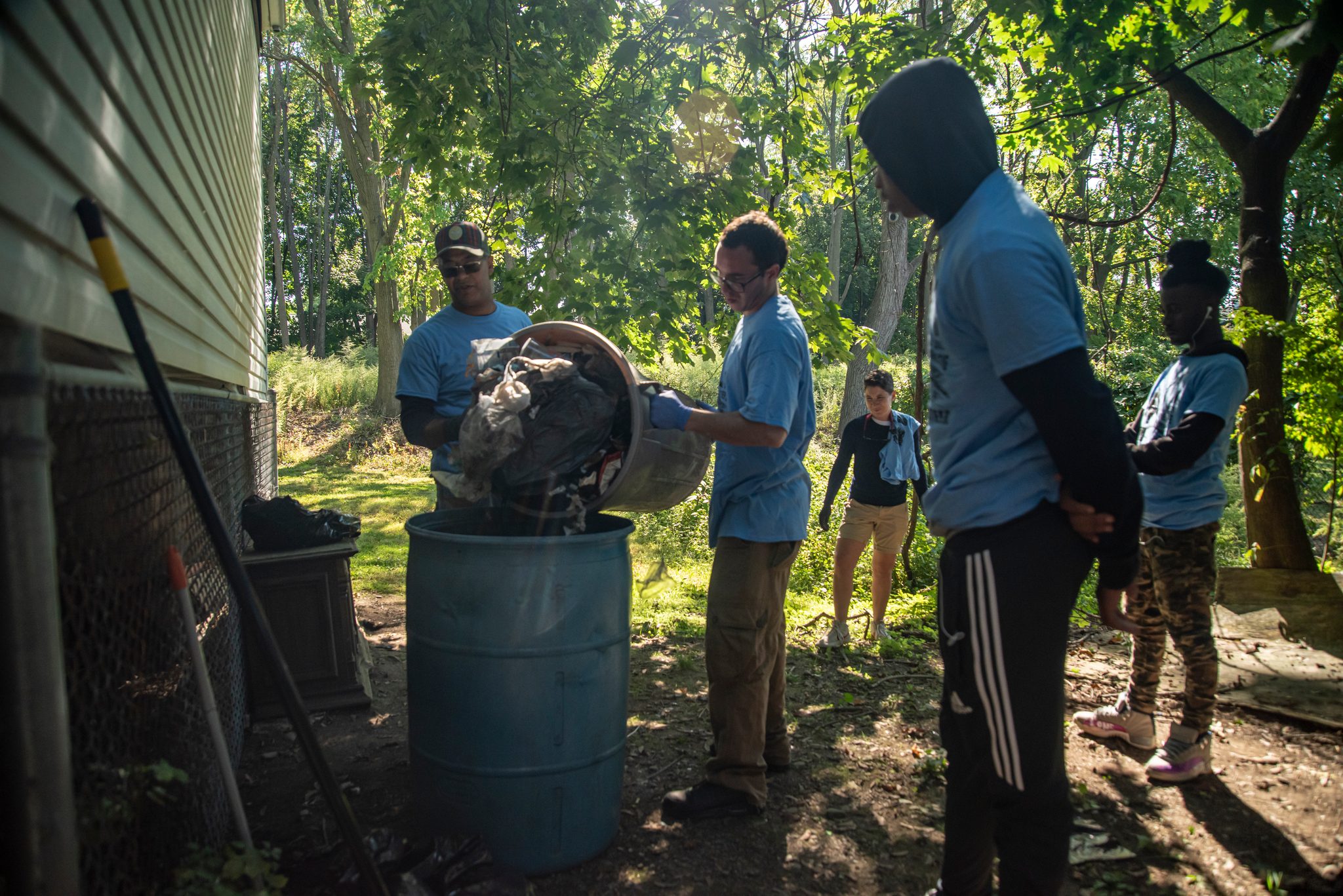 Volunteers in matching blue shirts empty their buckets into a barrel during the cleanup.