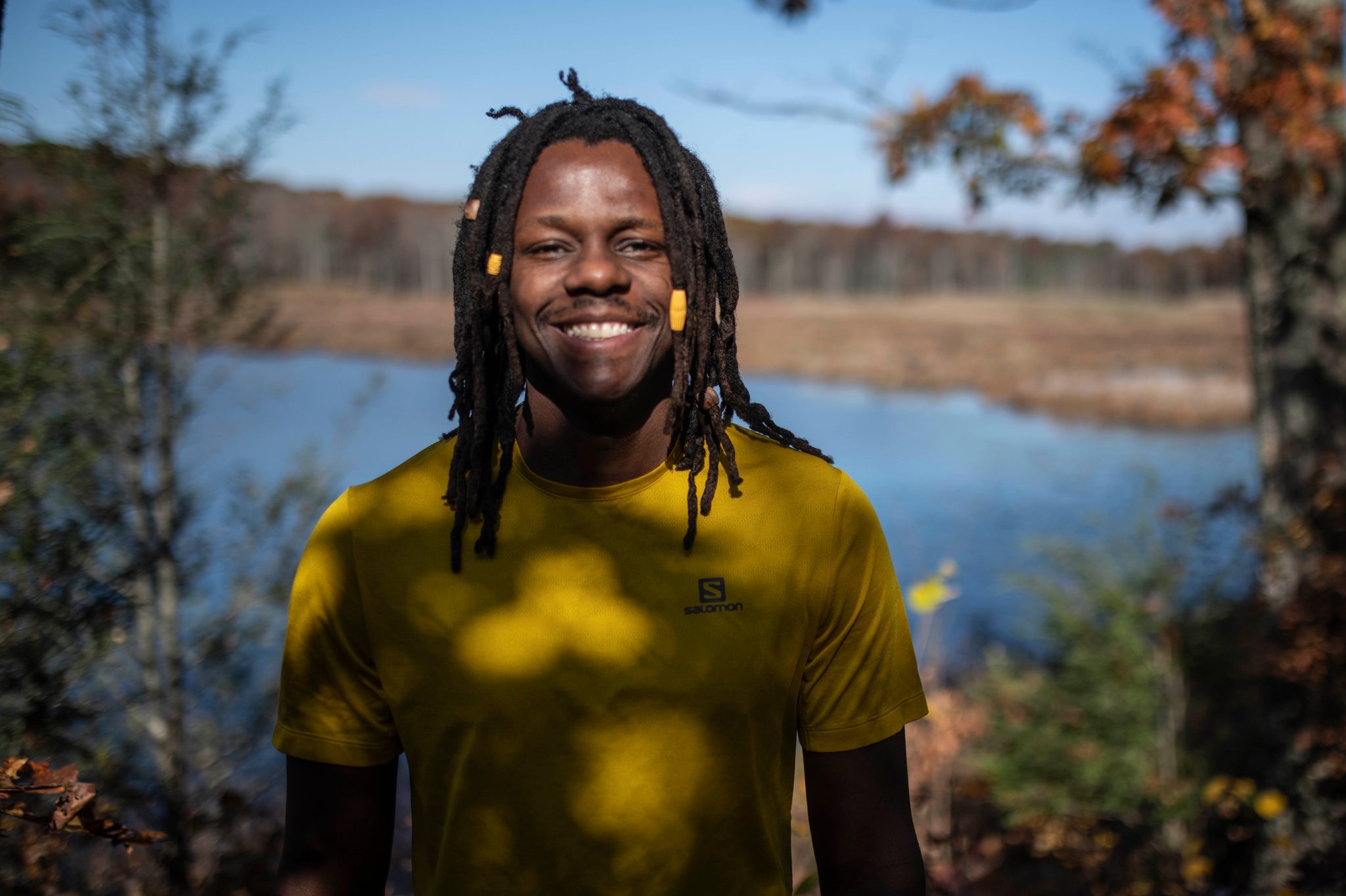 A still portrait of Chev in front of a marsh pond, fall colour on the far bank.