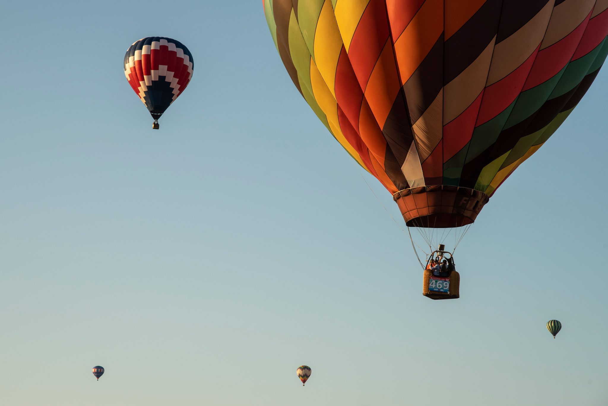 Balloons scatter across the evening sky, the nearest close enough to read its number.