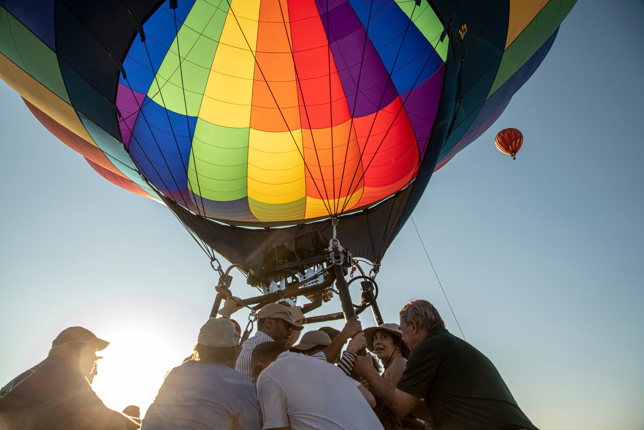 The rainbow balloon lifts off over the crew's heads, another already high in the sky.