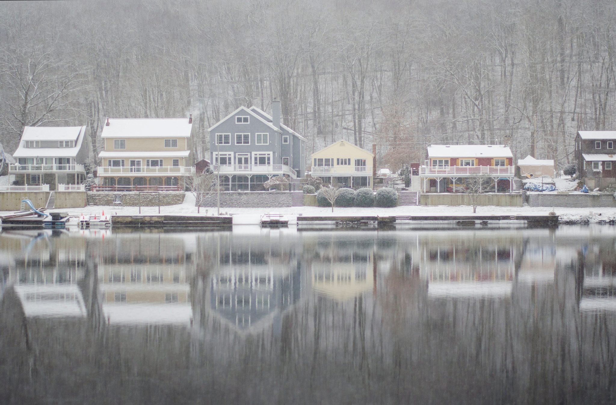 Snowy riverfront homes line up along the bank, their reflections trembling below.