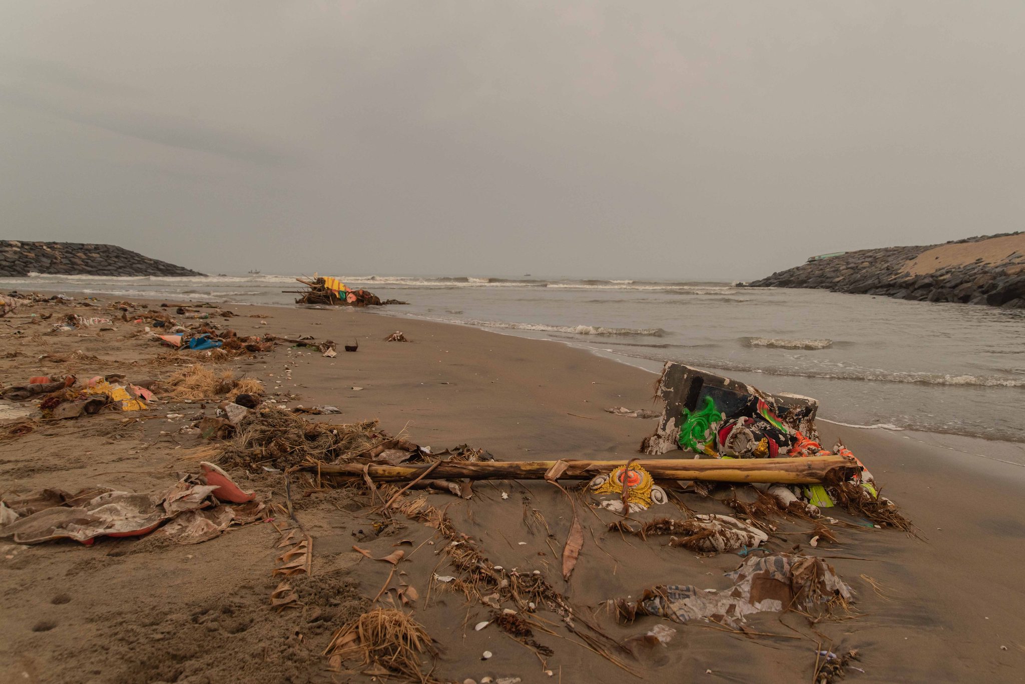Bamboo, marigolds and bright scraps lie washed up on the sand.