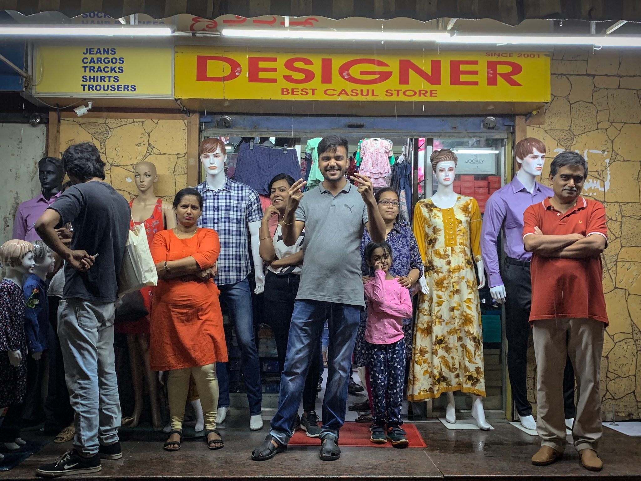 Shoppers and mannequins crowd the front of the Designer clothing store.