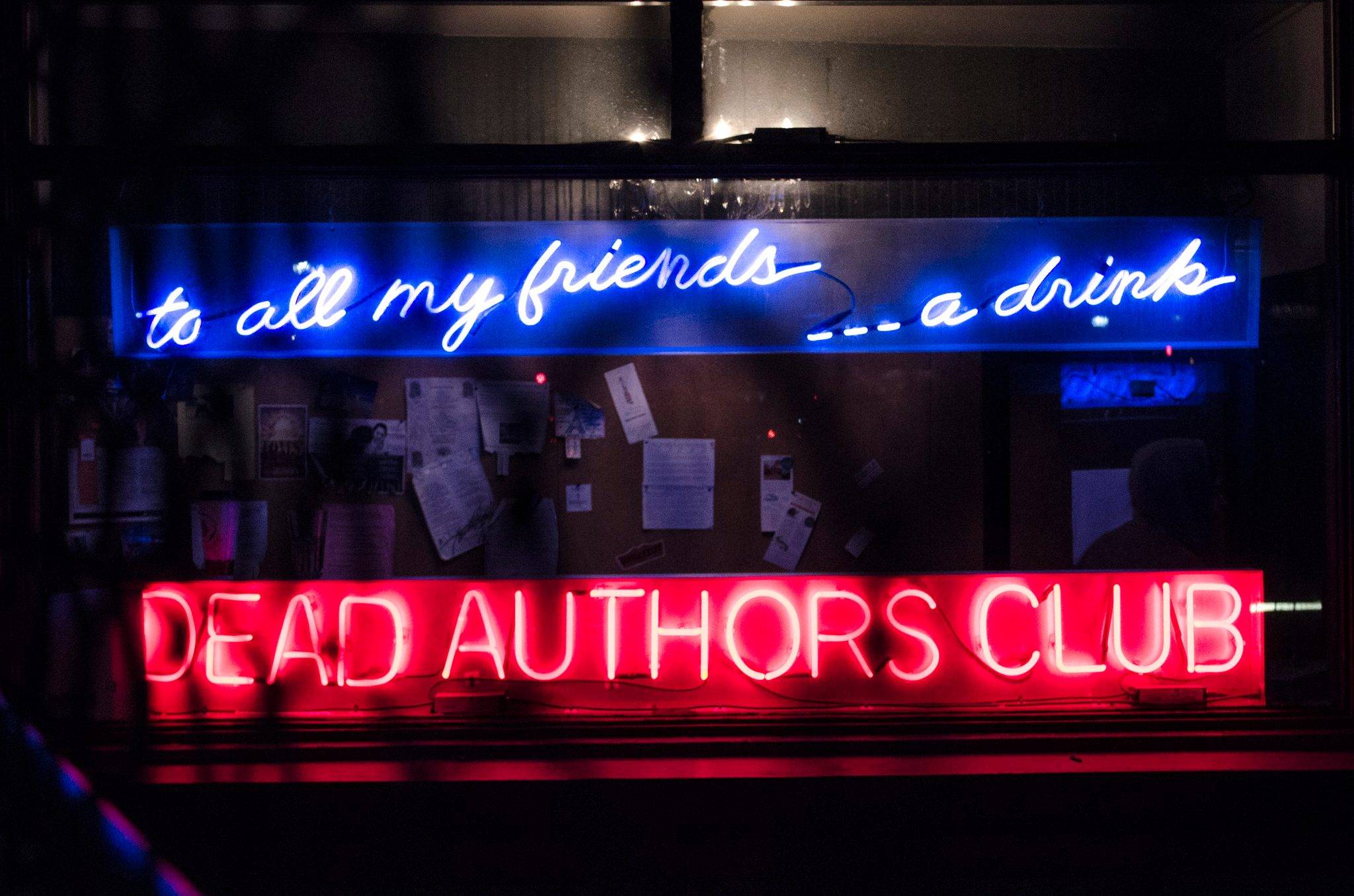 To all my friends... a drink, glows in blue neon above the red DEAD AUTHORS CLUB.
