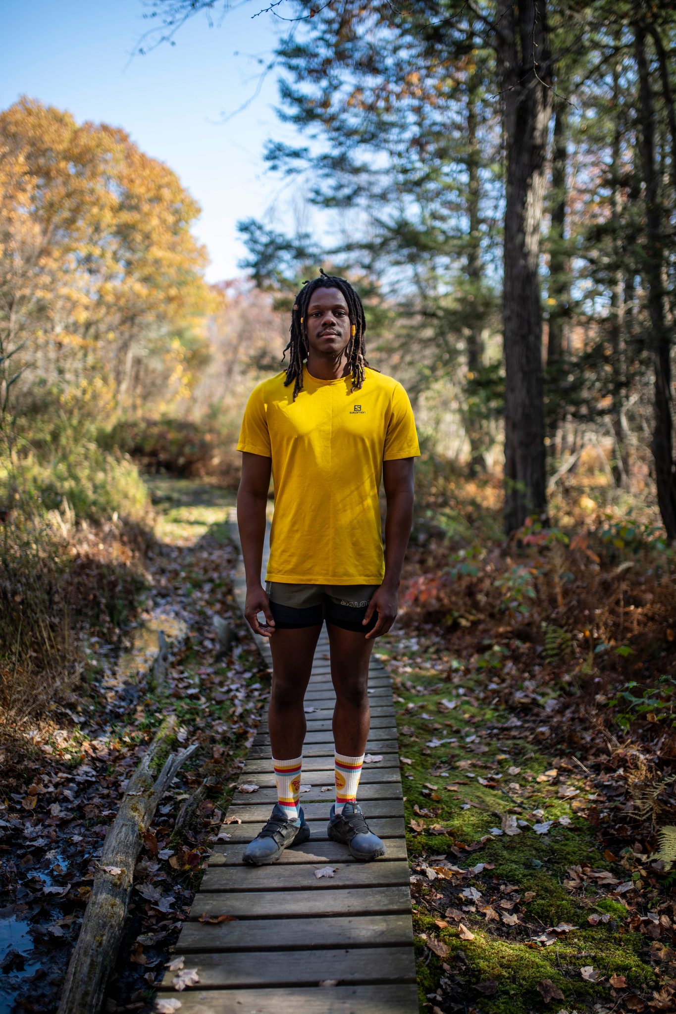 He stands at the end of a narrow boardwalk, the woods blazing around him.
