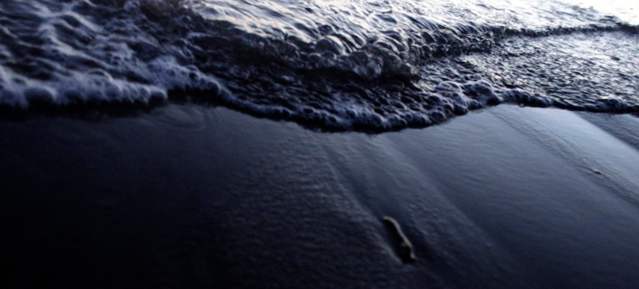 A wave slides back over wet black sand. It is empathy that allows us to bridge our oceans.