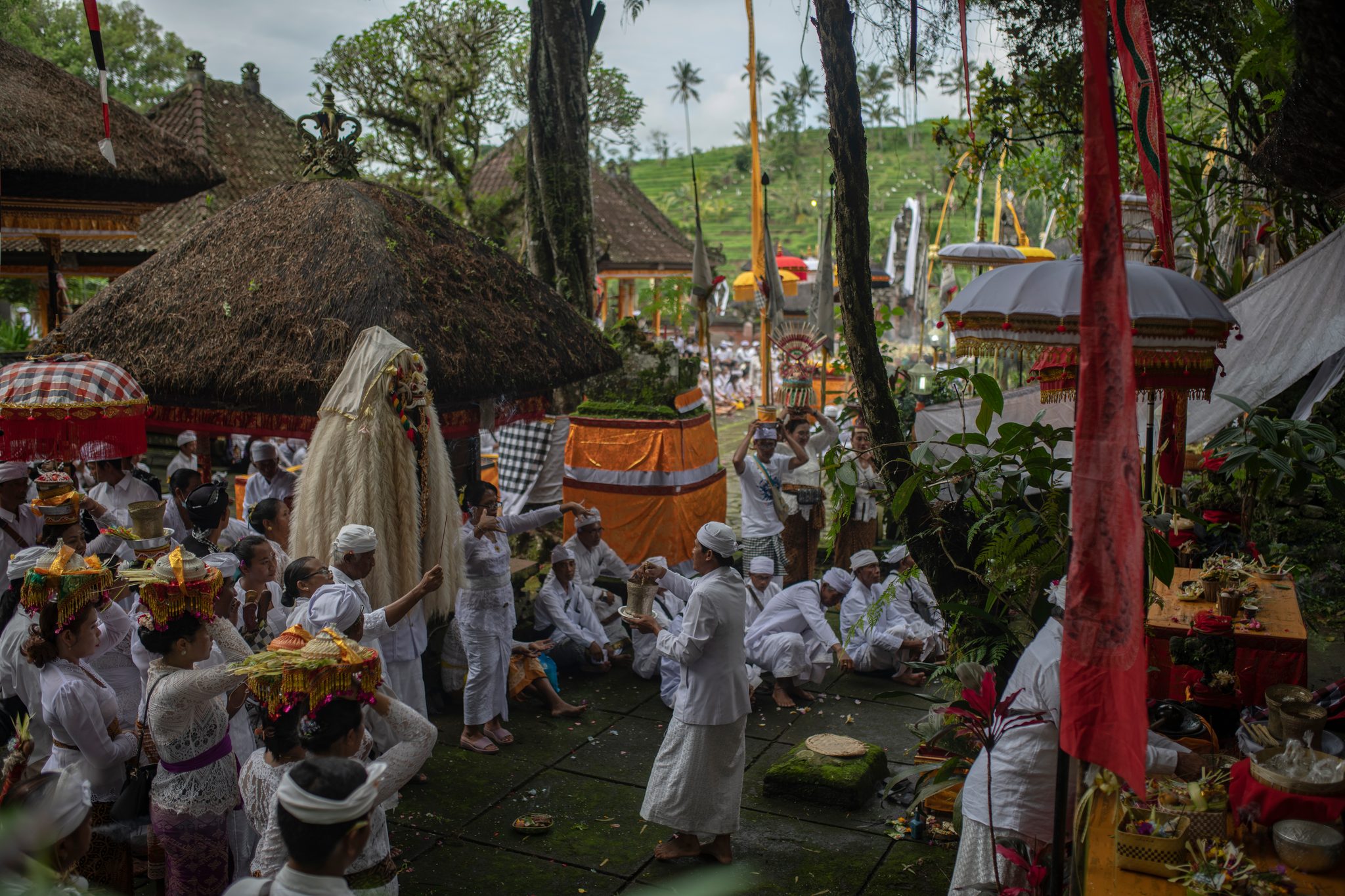 Under the thatched shrines of Pura Luhur Besikalung, the courtyard fills with offerings and white.