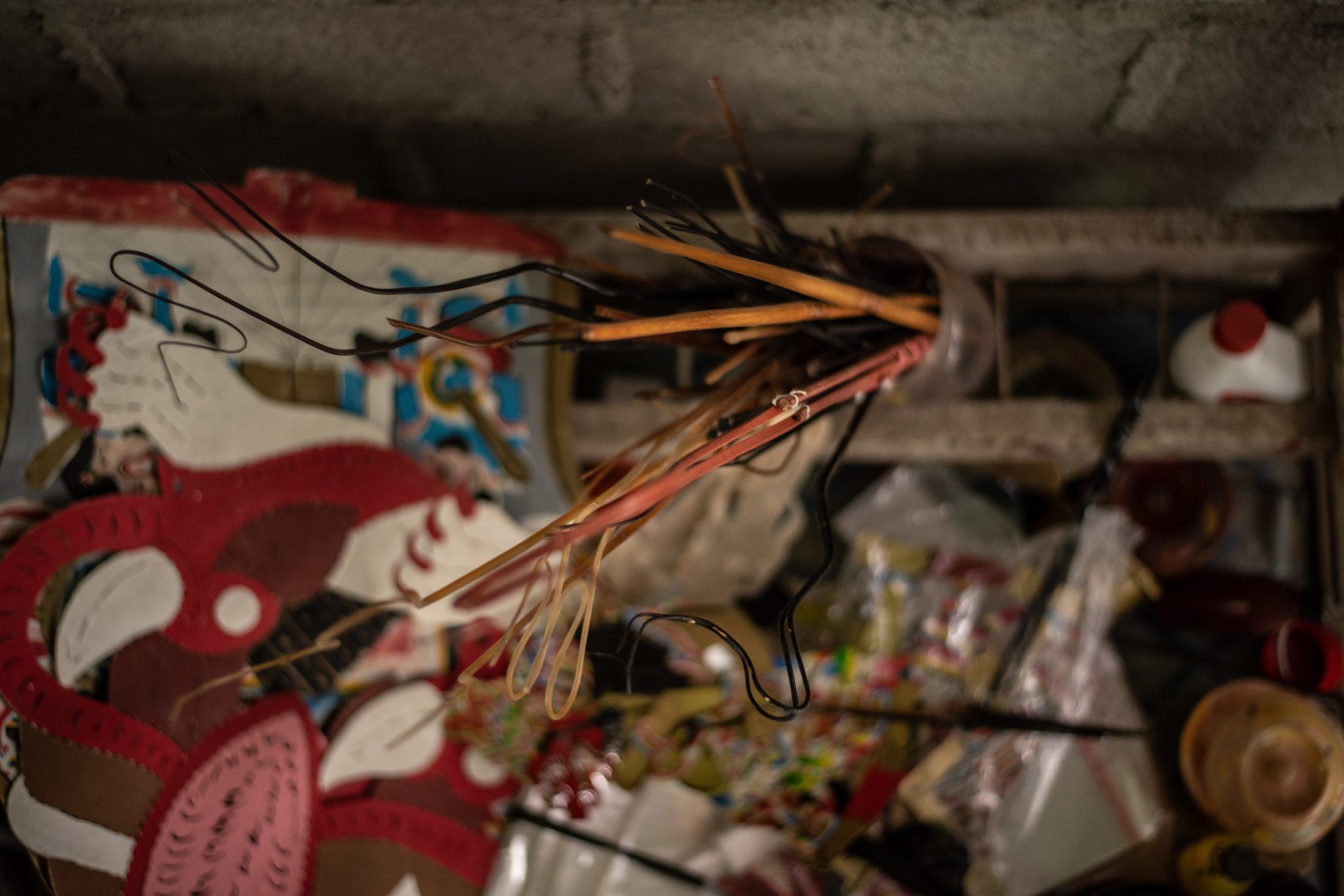 Painted puppets and their rods lie in a tangle, waiting to be joined.