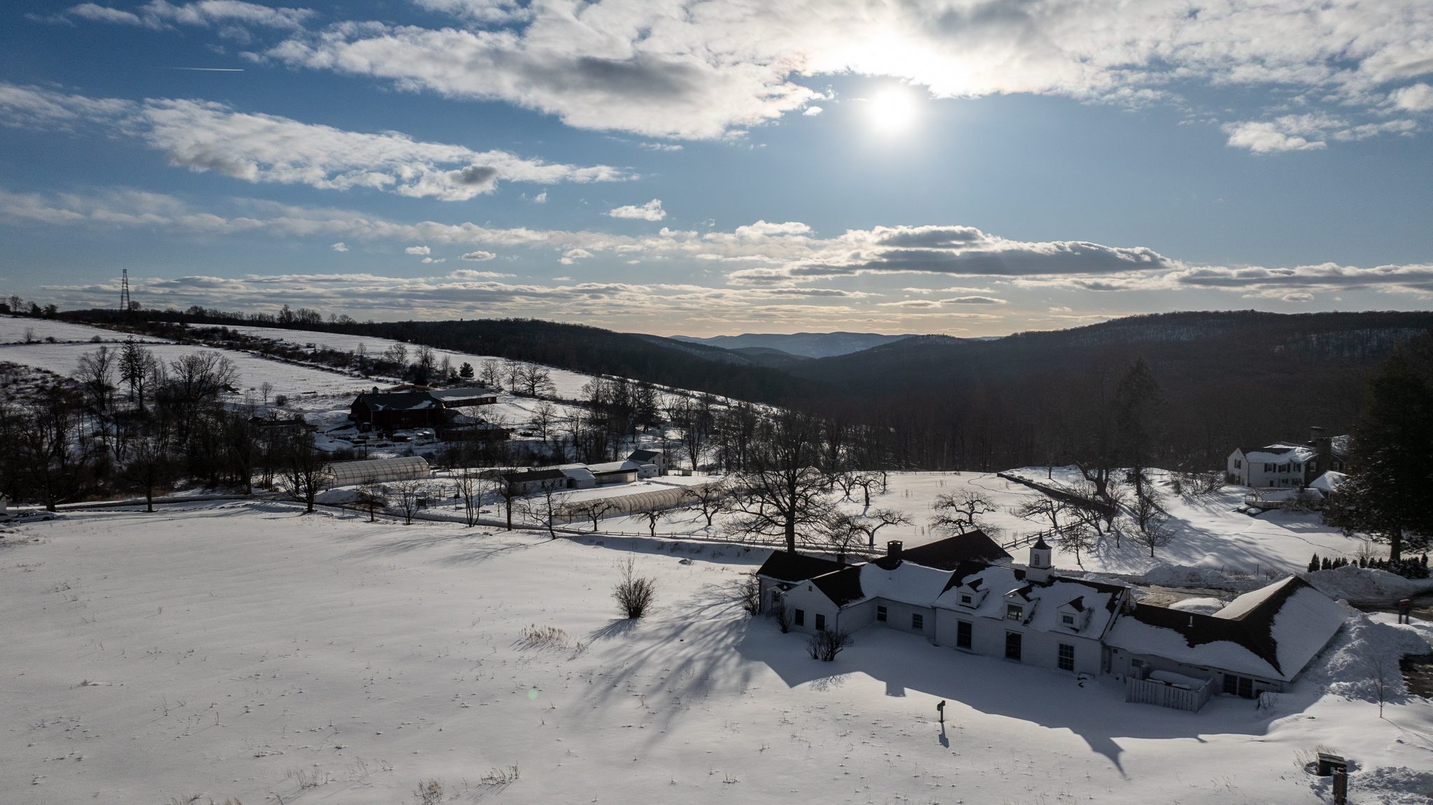 Afternoon sun over the snowfields and the long white farm buildings.