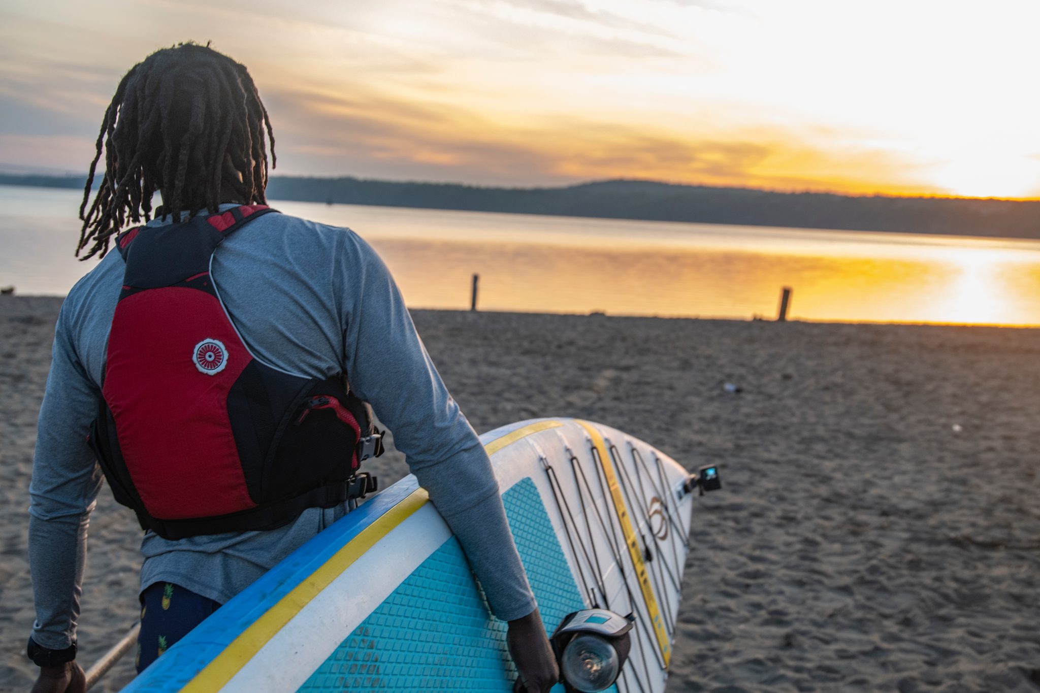 Board under one arm, Chev walks down the sand toward water turning gold with first light.