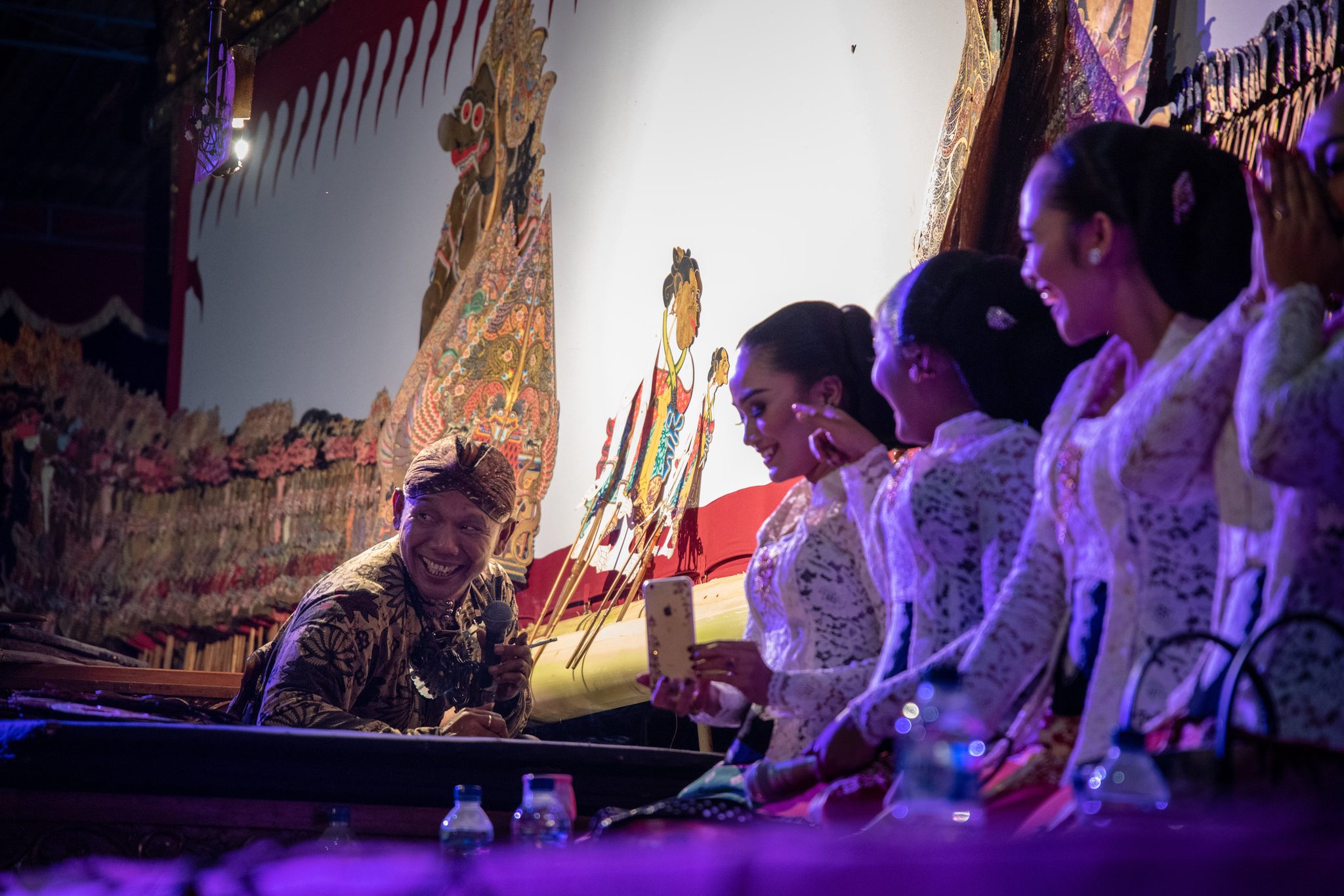 A grinning musician leans in as the singers pass a phone down the line.