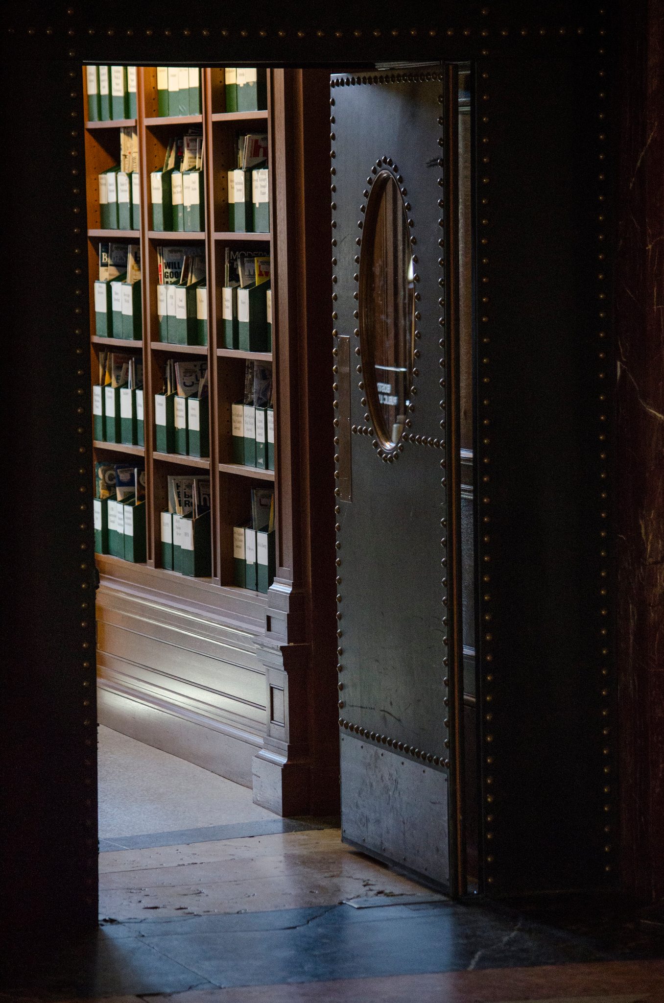 A heavy door stands open to shelves of archive boxes.